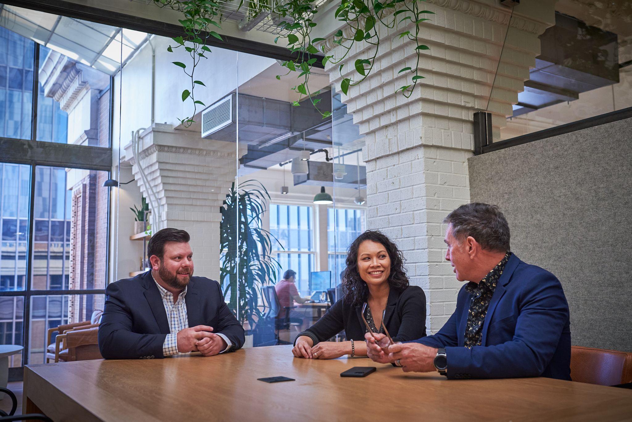 Colleagues talking around a table in a plant-filled meeting room — Team photography, Austin Colleagues talking around a table in a plant-filled meeting room