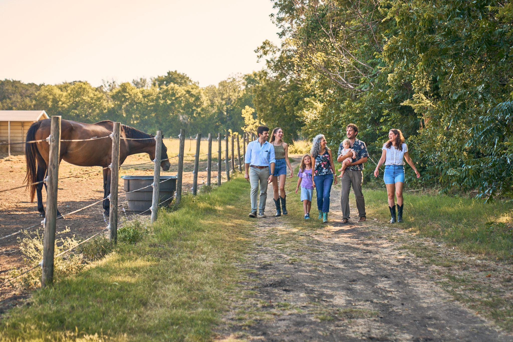 Family walking a fence-lined trail through a field — Adventure & outdoor photography, Austin A family walking a fence-lined trail through a field.
