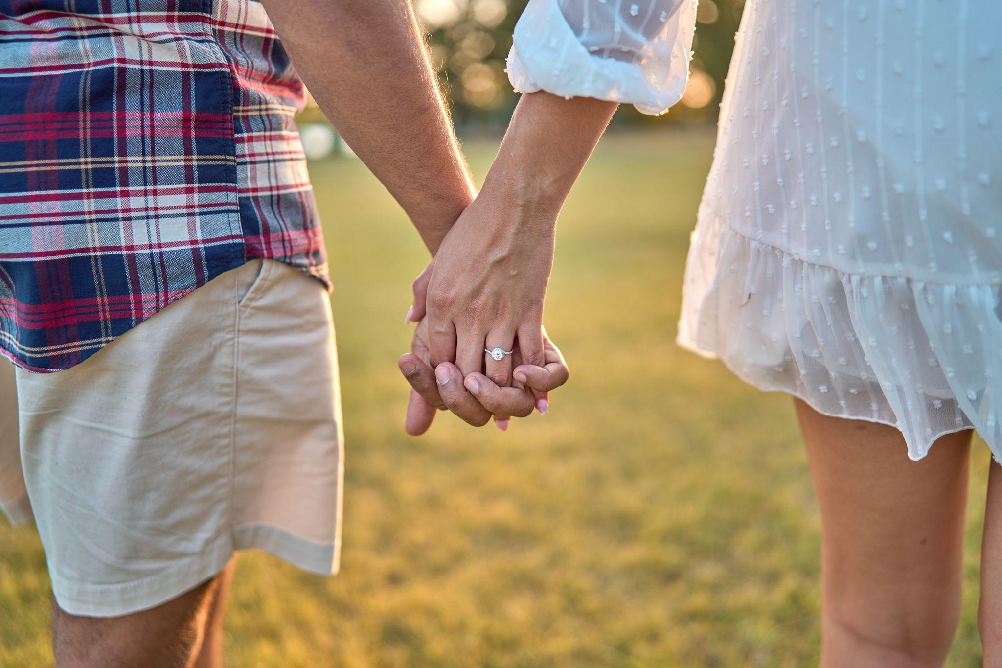 Close frame of a couple's joined hands with an engagement ring, meadow grass — Brushy Creek Lake Park photography, Austin A close frame of a couple's joined hands with an engagement ring, meadow grass behind