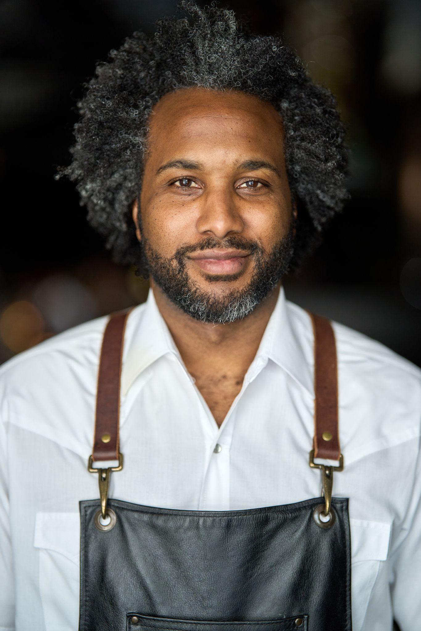 Chef in a white shirt and leather apron smiling in his kitchen — Headshot photography, Austin A chef in a white shirt and leather apron smiling in his kitchen.