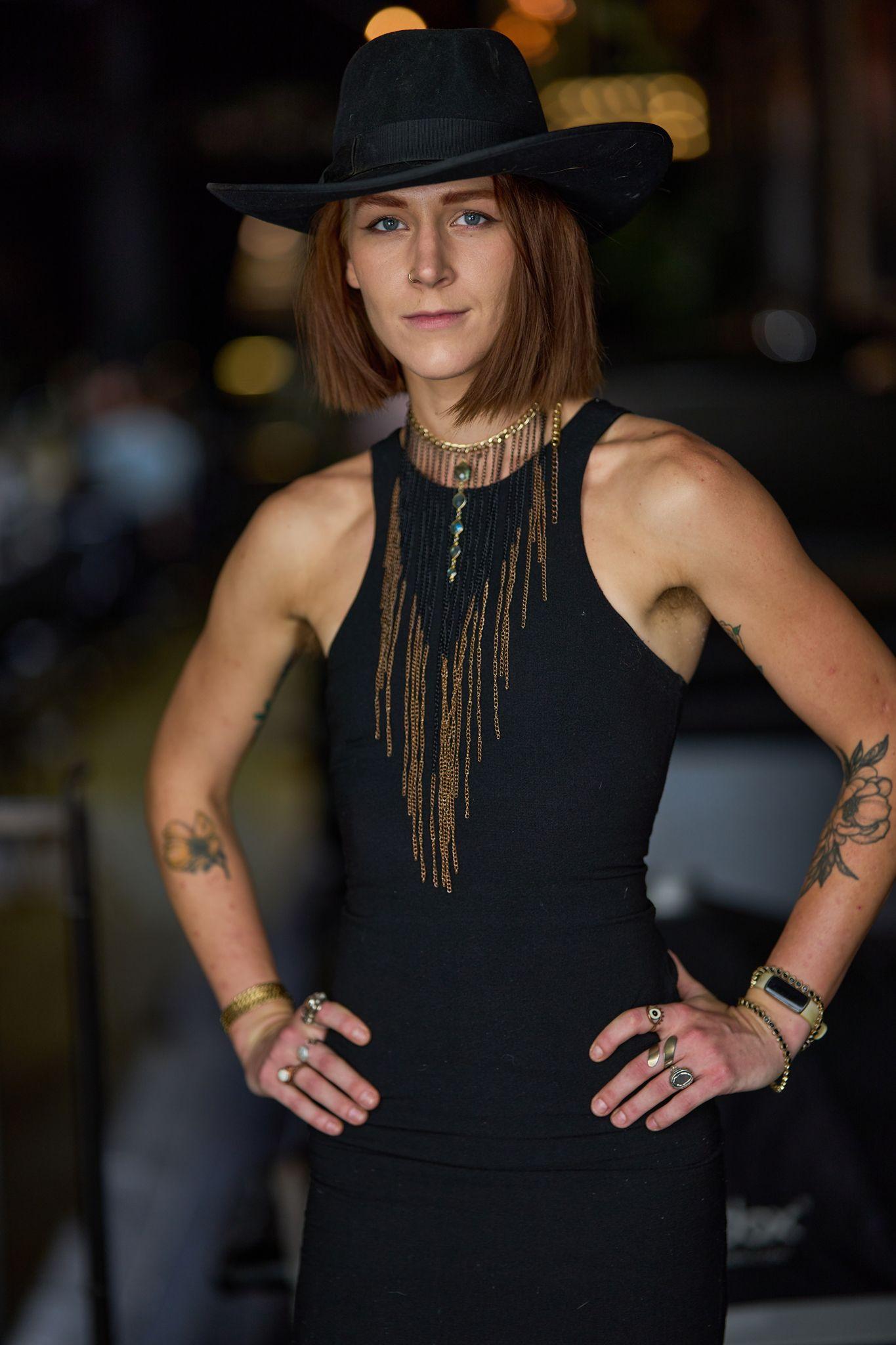 Woman in a black hat and sleeveless top standing with her hands on her hips — Portrait photography, Austin A woman in a black hat and sleeveless top standing with her hands on her hips.