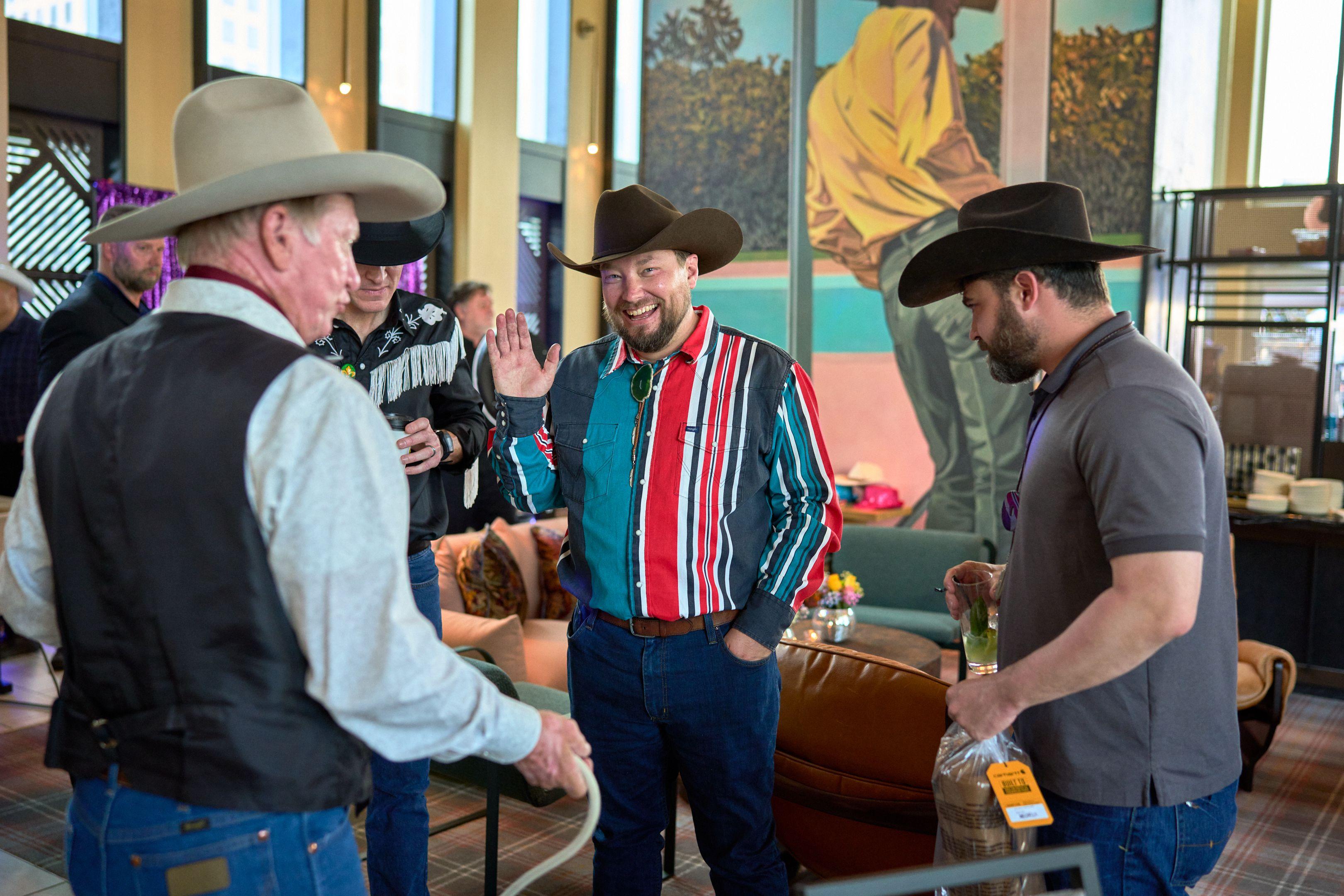 Guest in a striped western shirt and cowboy hat greeting friends at a themed party — Business Parties photography, Austin A guest in a striped western shirt and cowboy hat greeting friends at a themed party.