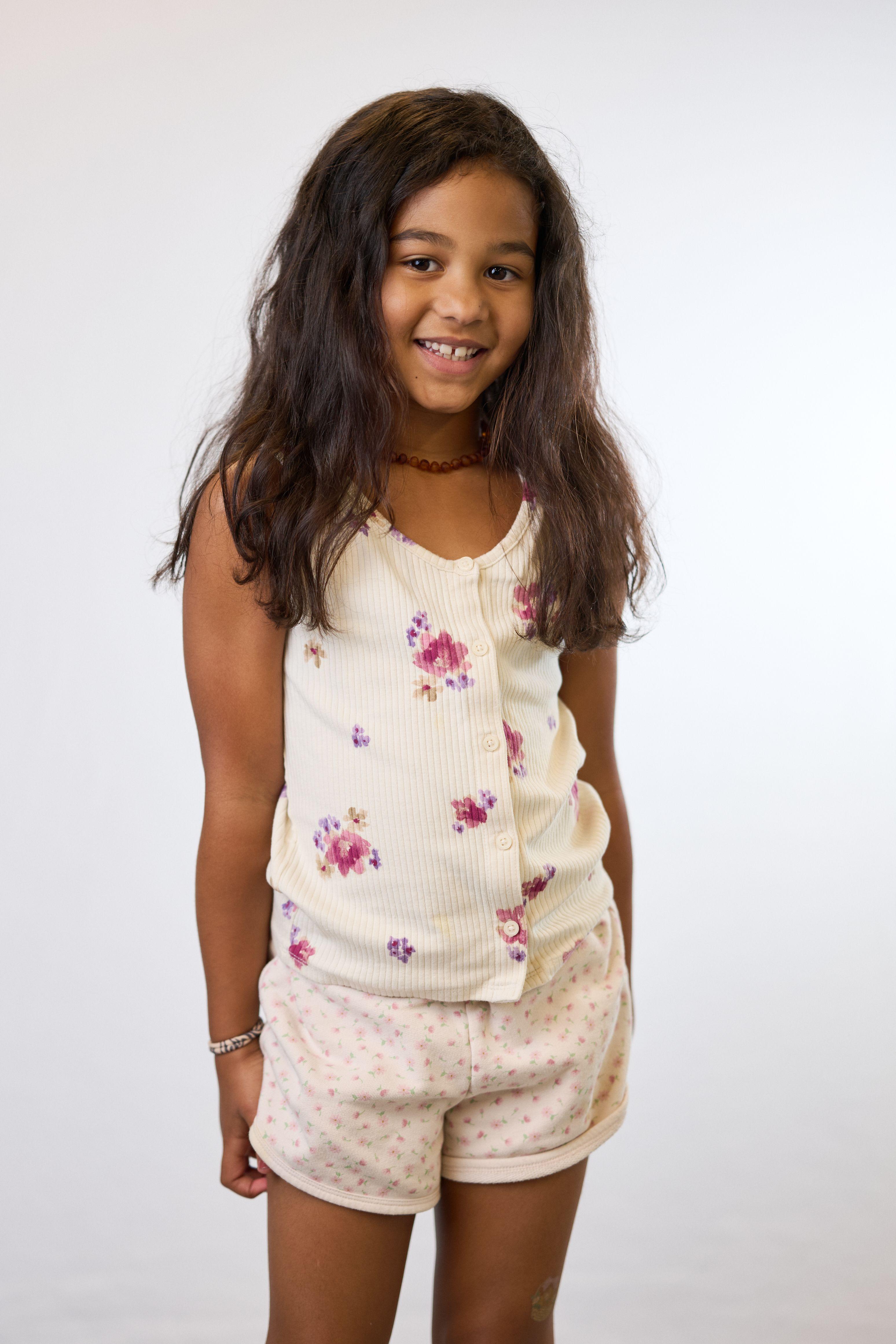 Girl in a floral vest and shorts standing on white seamless — Commercial photo studio, Austin Girl in a floral vest and shorts standing on white seamless