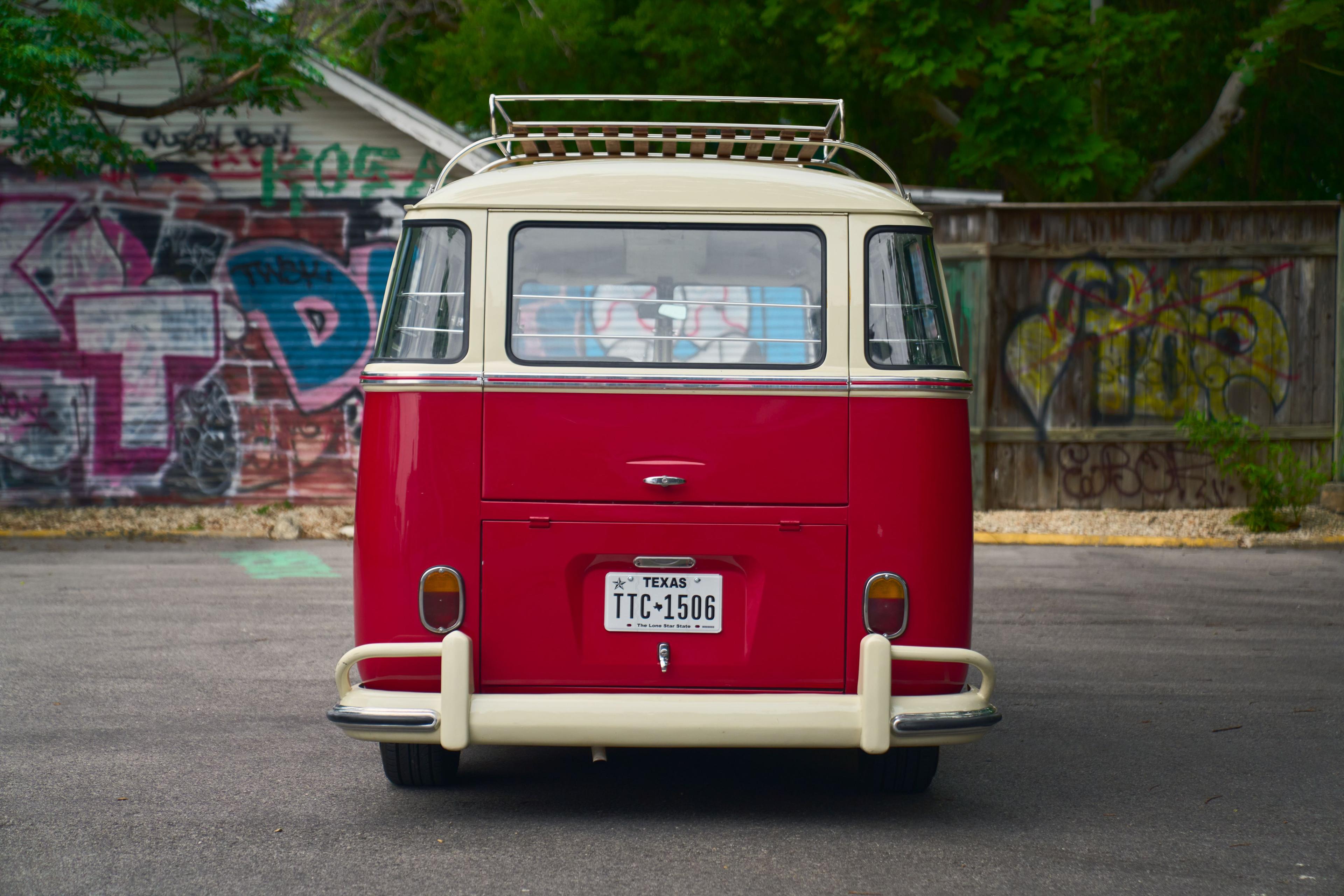 Rear of a red and white classic Volkswagen split-window bus with a roof rack — Automotive photography, Austin The rear of a red and white classic Volkswagen split-window bus with a roof rack.