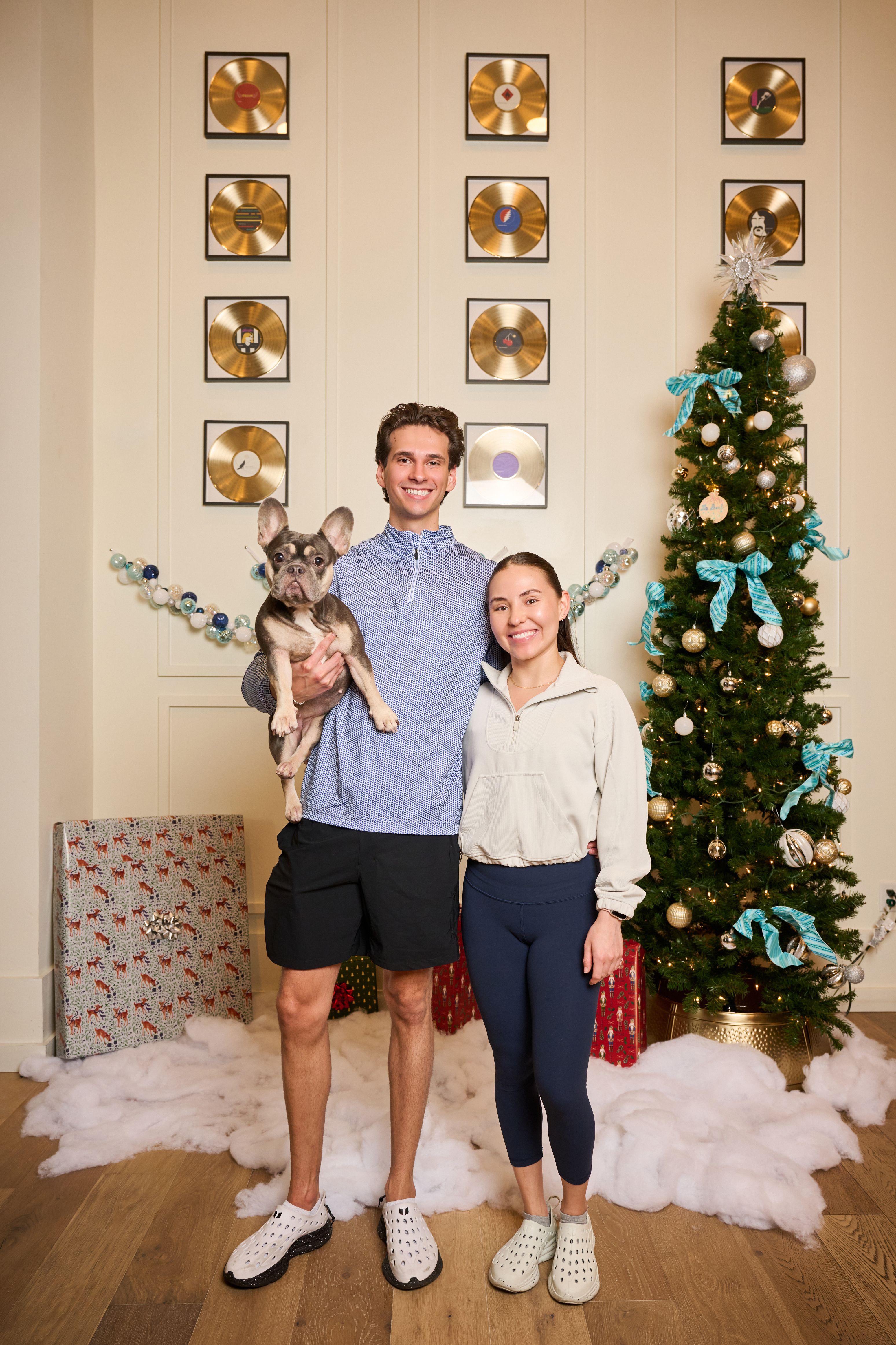 Couple holding a cat between them in front of a Christmas tree and beaded garland — Mobile photo studio, Austin A couple holding a cat between them in front of a Christmas tree and beaded garland