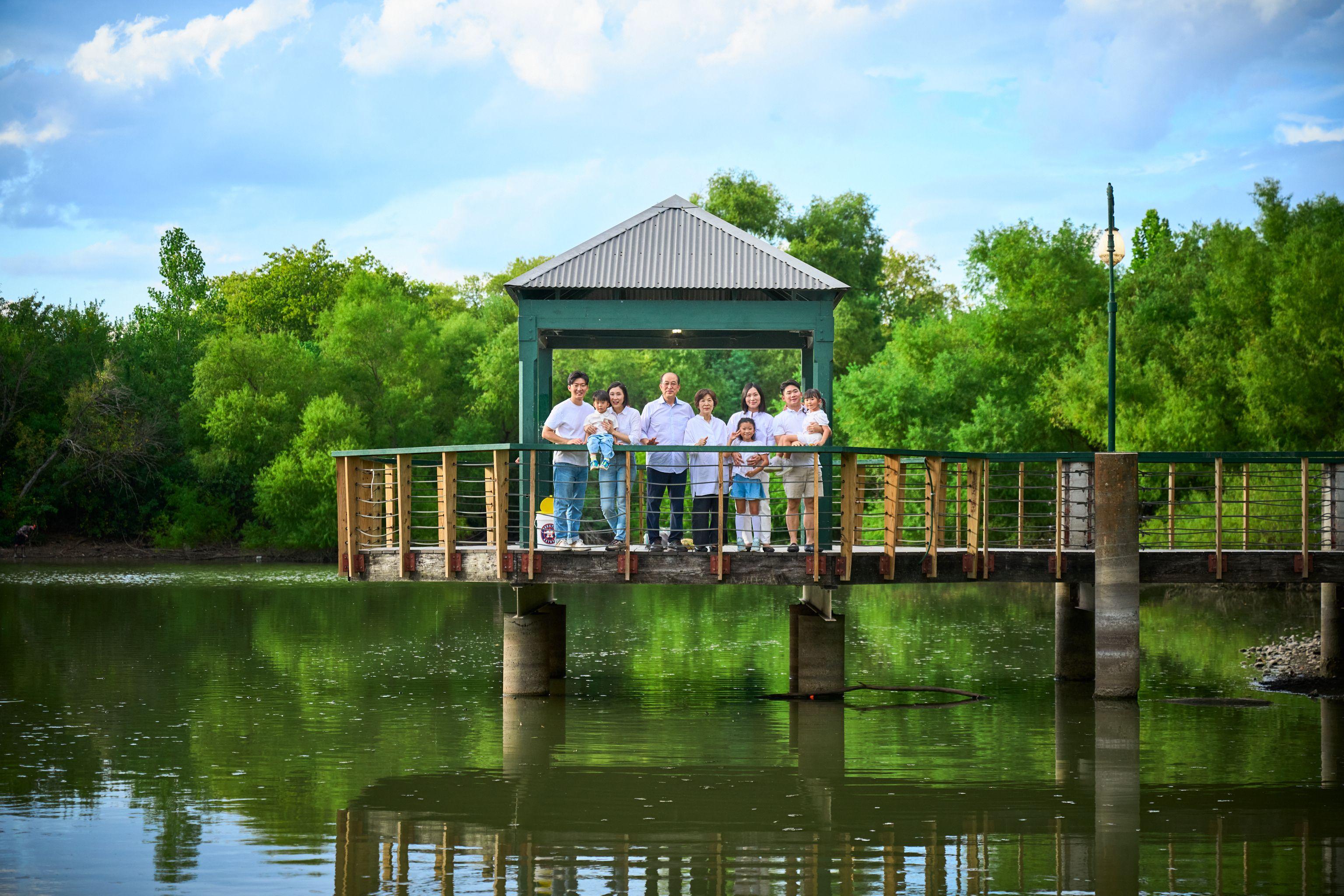 Covered pavilion out over the water at Mills Pond with a family standing in it — Mills Pond photography, Austin The covered pavilion out over the water at Mills Pond with a family standing in it, willows reflected around them
