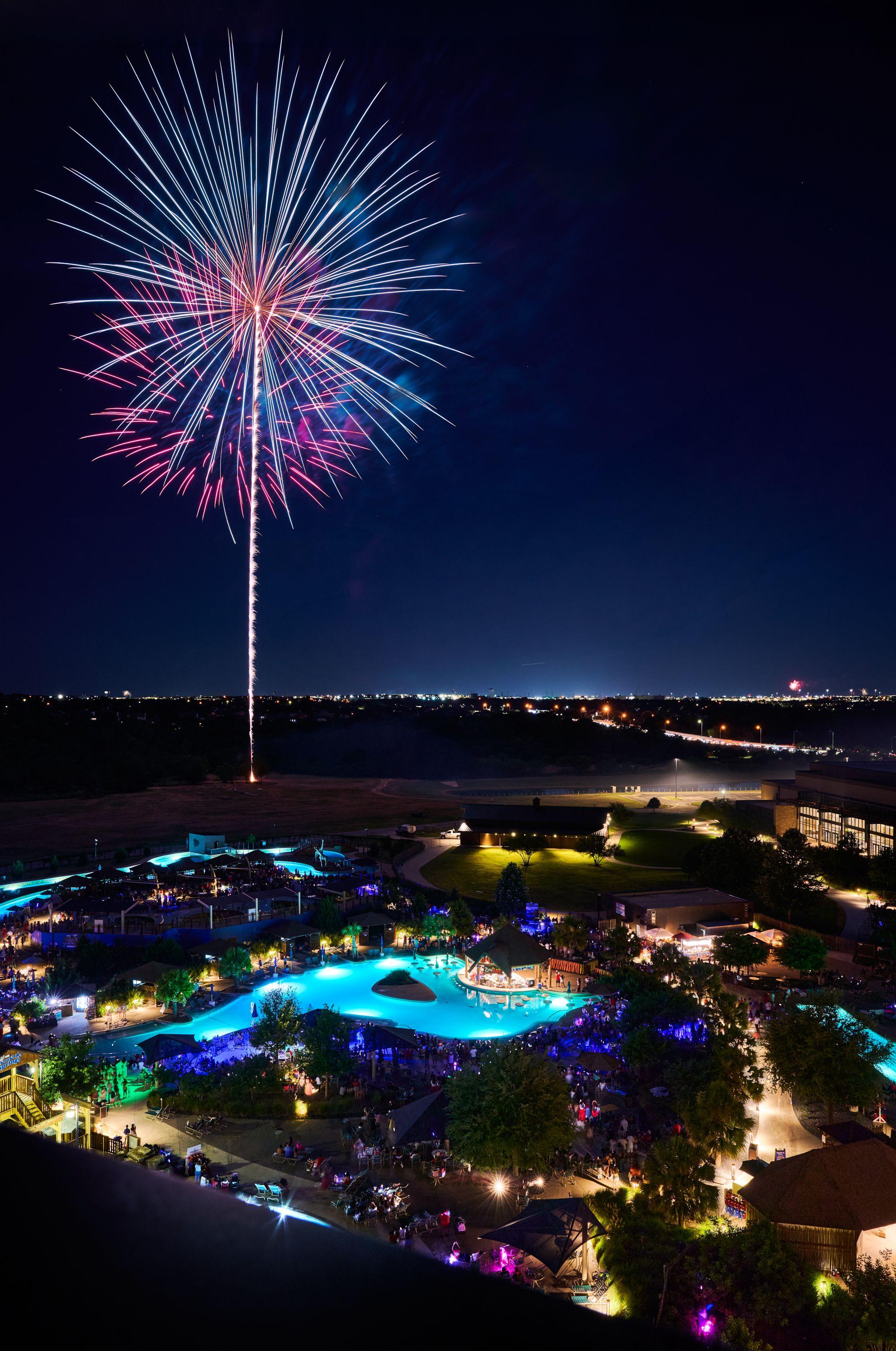 Single firework trail climbing above an illuminated resort at night — Festival photography, Austin A single firework trail climbing above an illuminated resort at night.