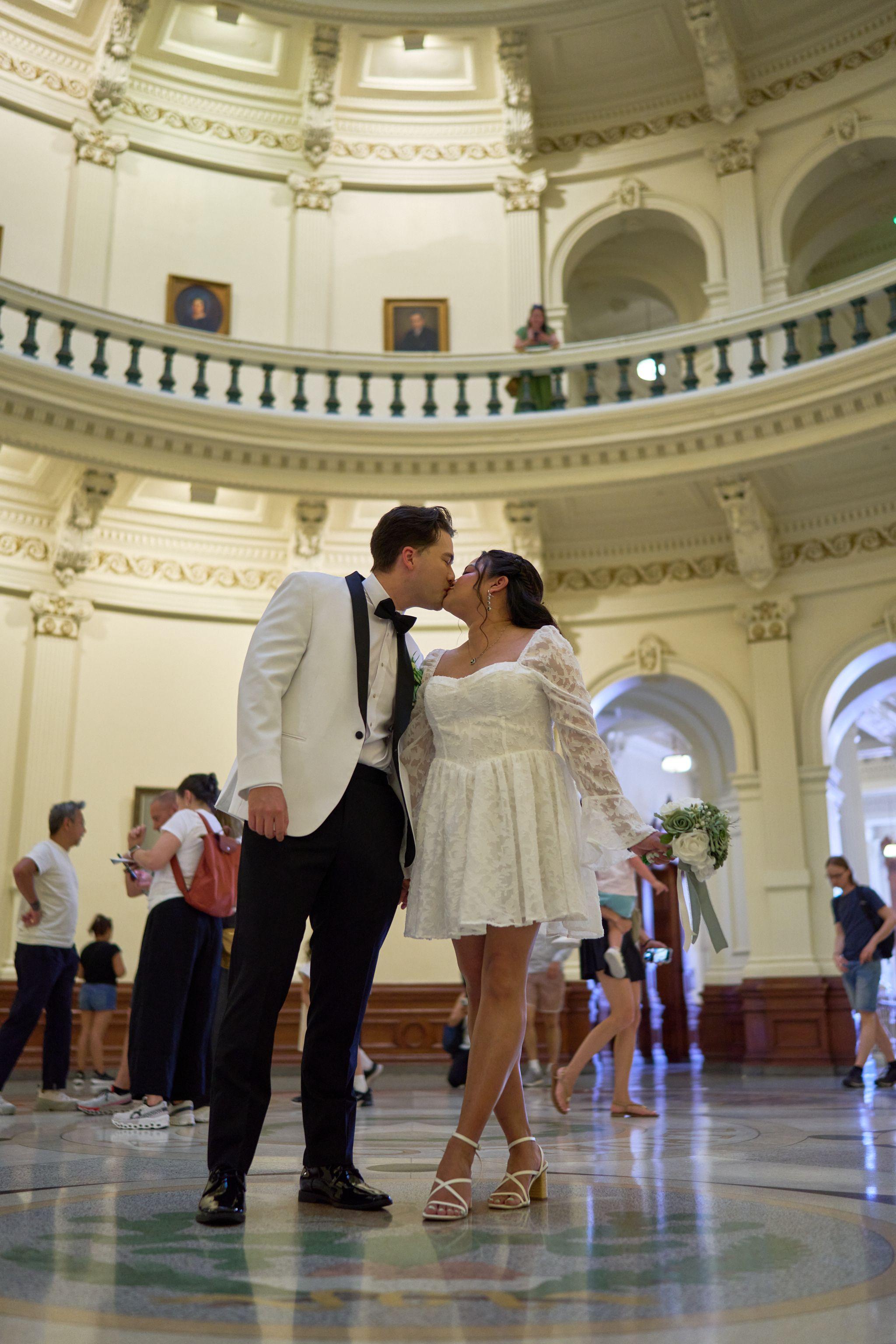 Couple kissing in the Capitol rotunda, the tiered galleries rising behind them — Texas State Capitol photography, Austin A couple kissing in the Capitol rotunda, the tiered galleries rising behind them.