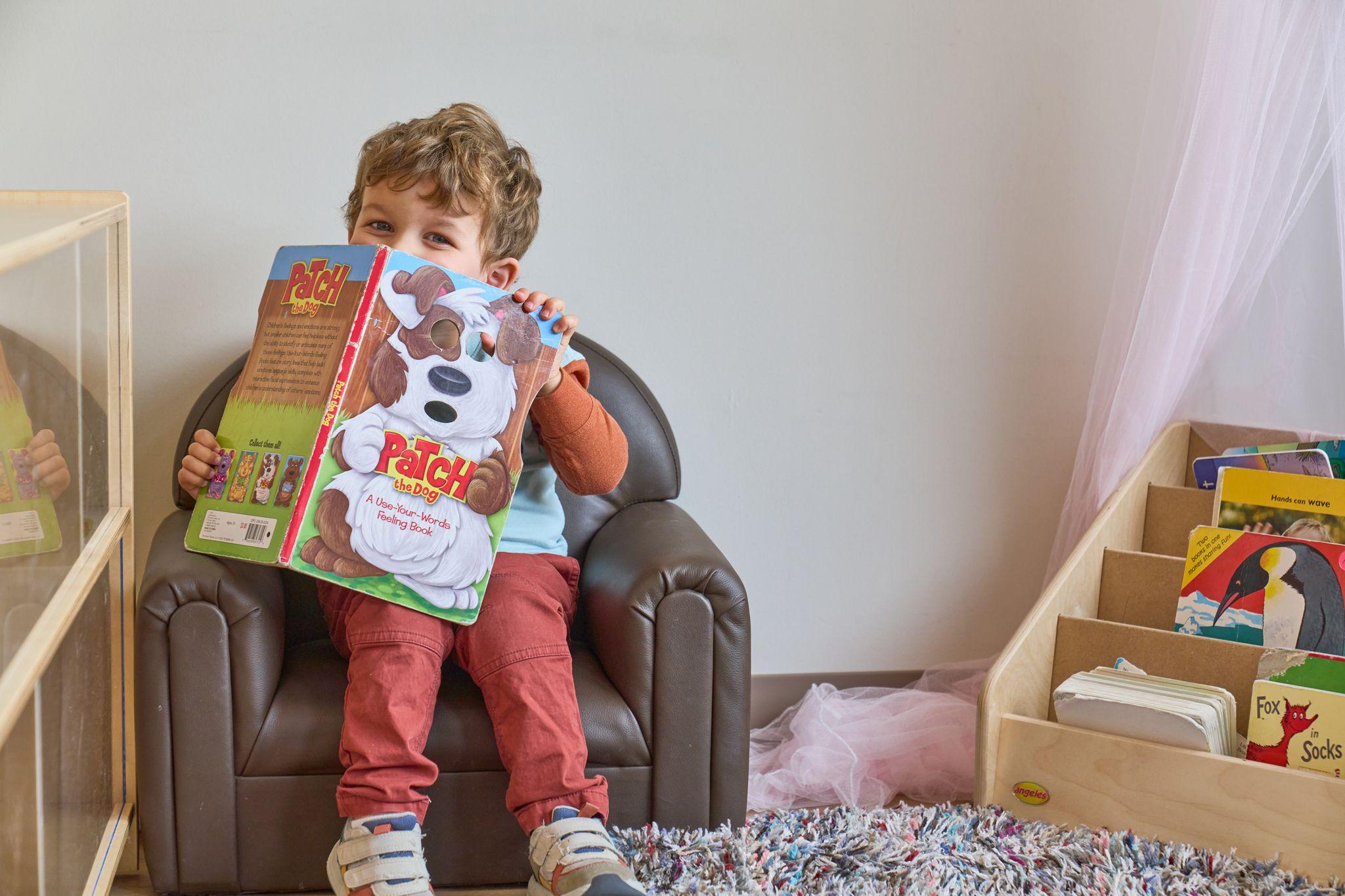 Boy standing on a chair holding a large picture book — Kids Portraits photography, Austin A boy standing on a chair holding a large picture book.