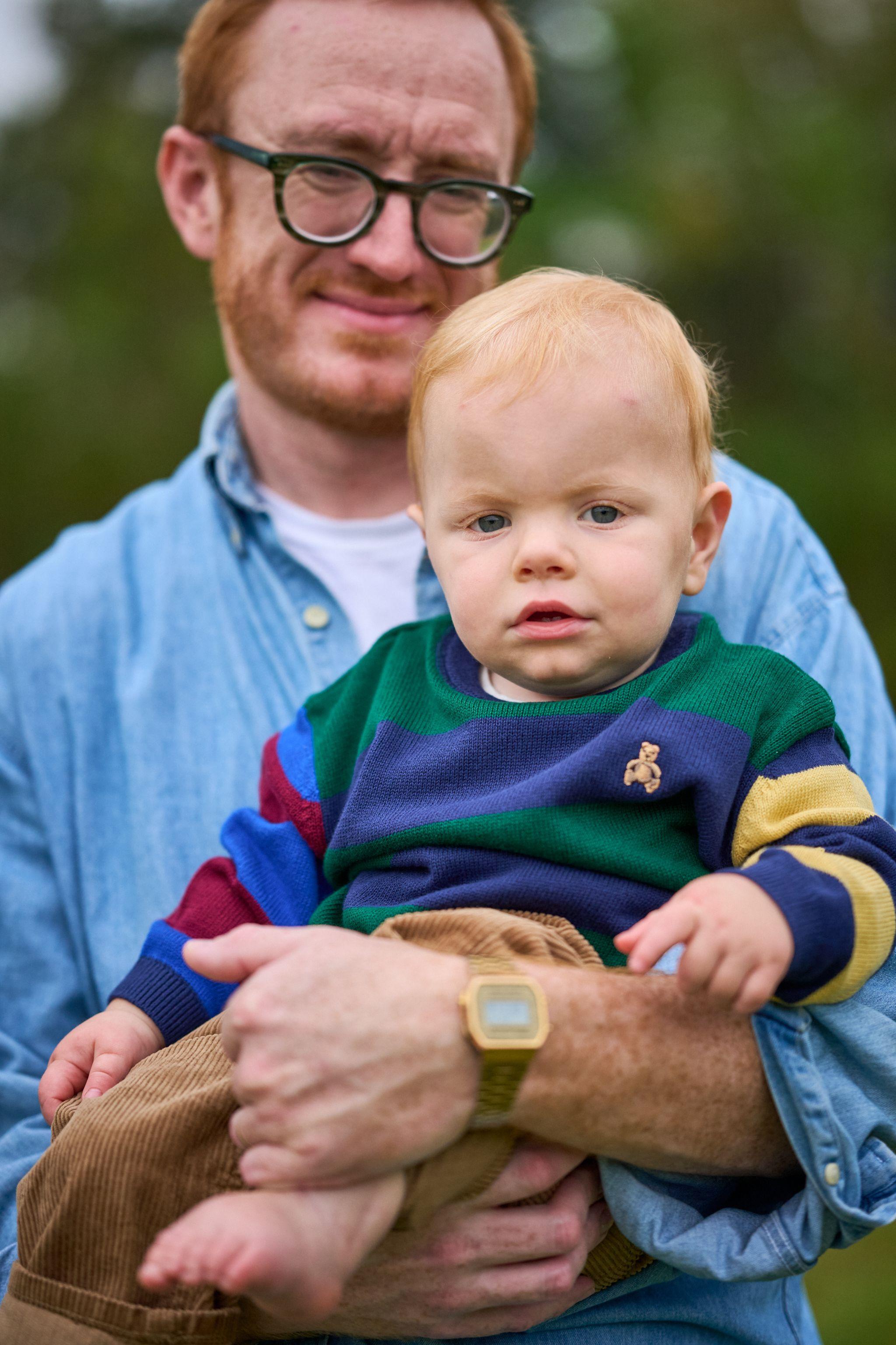 Father holding his toddler, who wears a color-blocked jumper, to camera — Waterloo Park photography, Austin A father holding his toddler, who wears a color-blocked jumper, to camera.