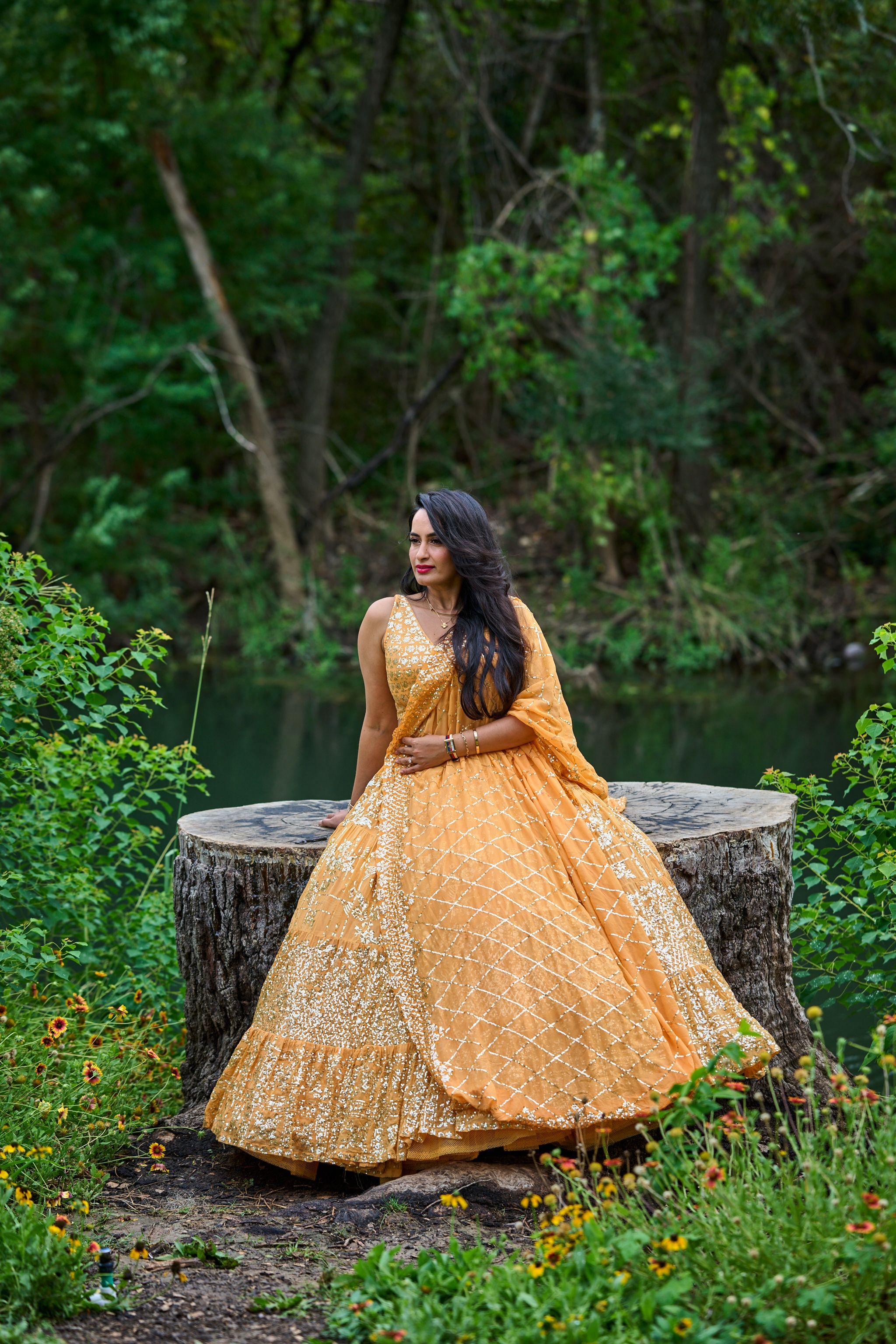 Woman in a gold lehenga turning on a tree stump, her skirt sweeping out around — Cedar Park Public Library photography, Austin A woman in a gold lehenga turning on a tree stump, her skirt sweeping out around her, at the Cedar Park library