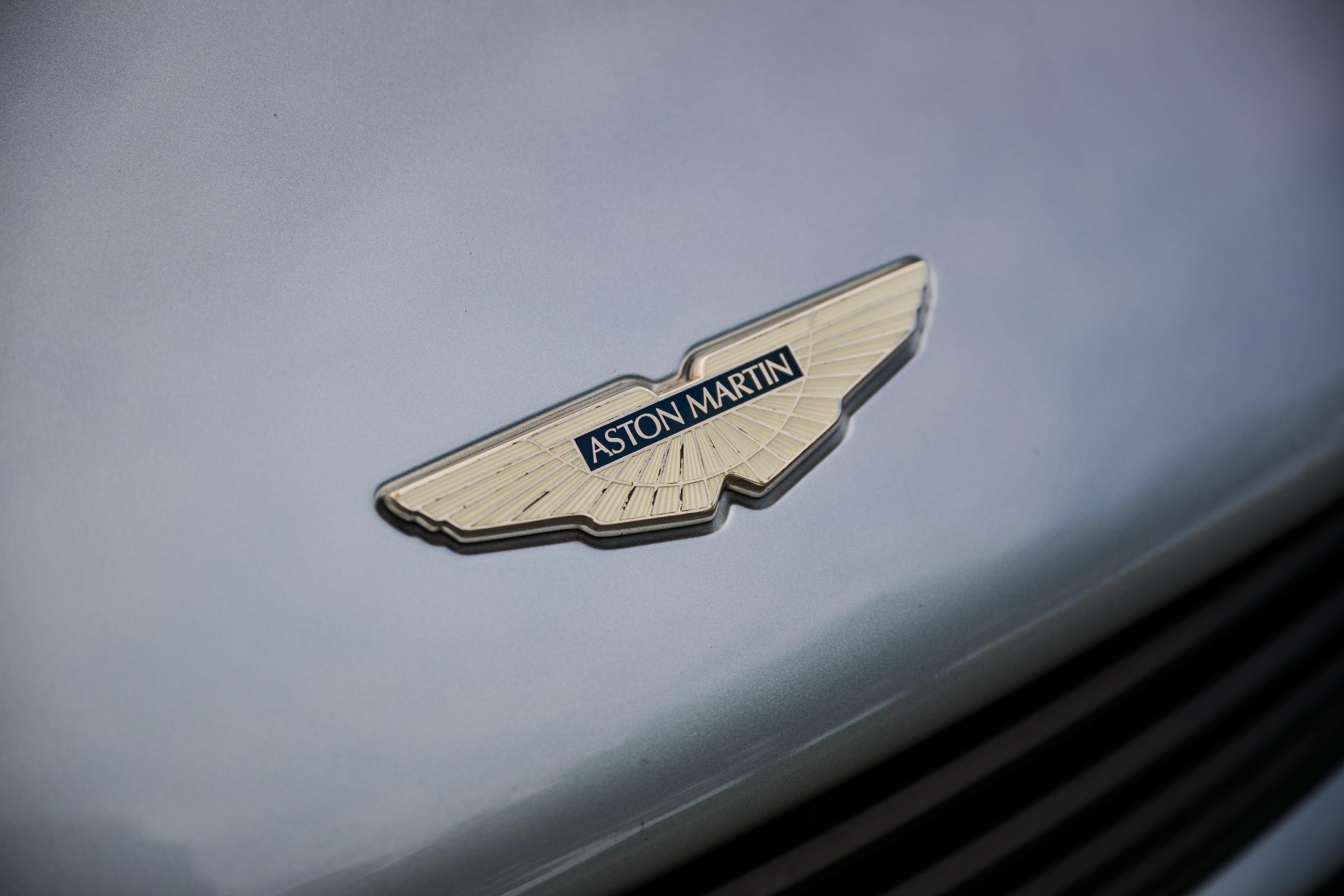 Close detail of the Aston Martin winged badge on a silver bonnet — Automotive photography, Austin A close detail of the Aston Martin winged badge on a silver bonnet.