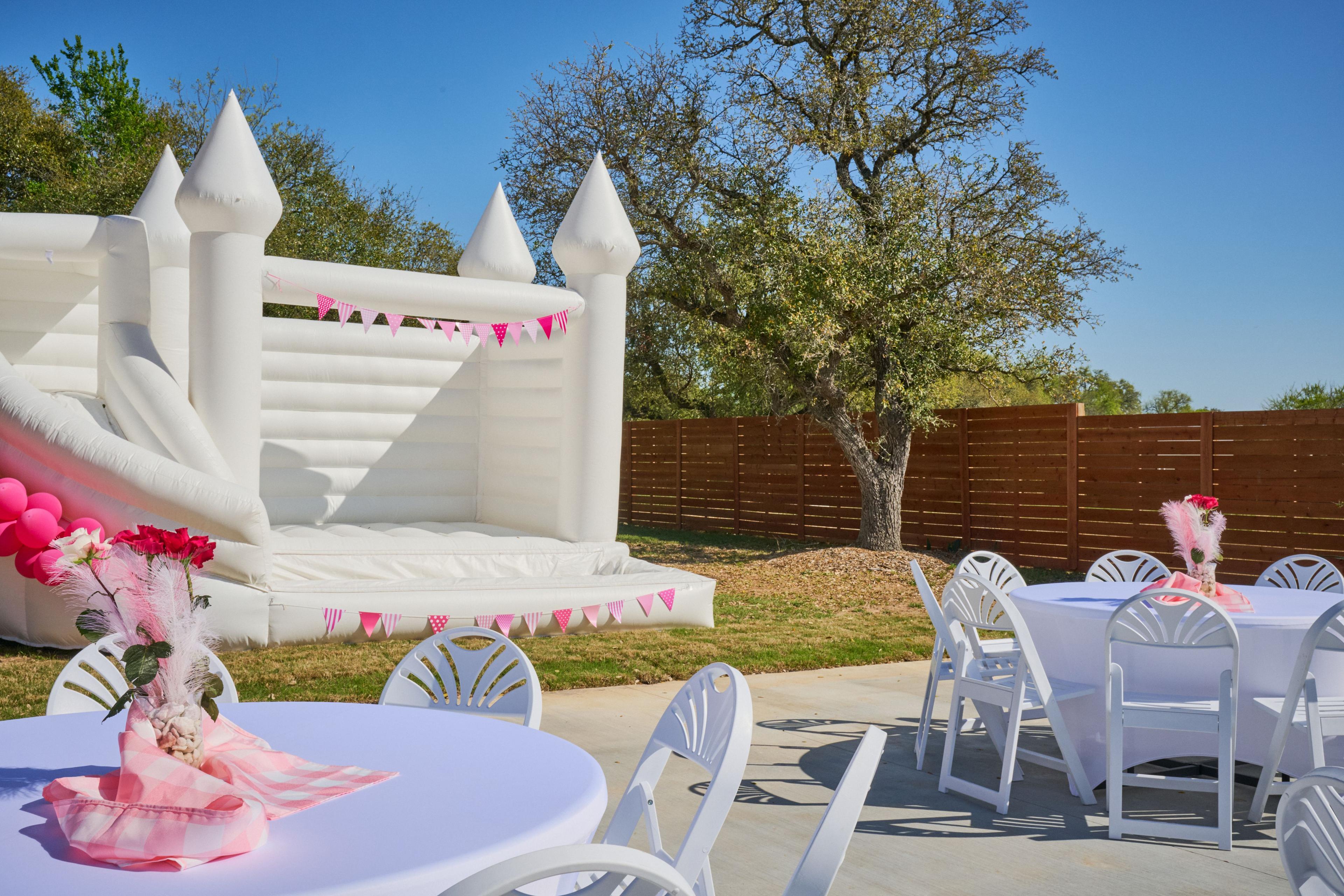 White bounce castle and pink bunting set up on a lawn for a children's party — Family Parties photography, Austin A white bounce castle and pink bunting set up on a lawn for a children's party.