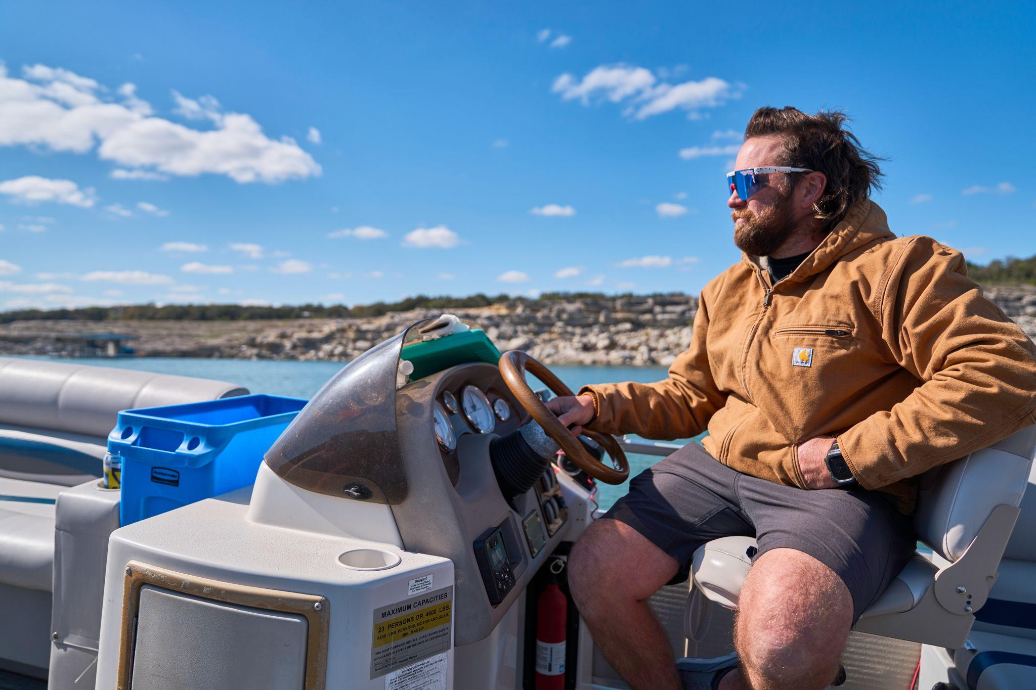 Man in sunglasses driving a boat on open water — Adventure & outdoor photography, Austin A man in sunglasses driving a boat on open water.