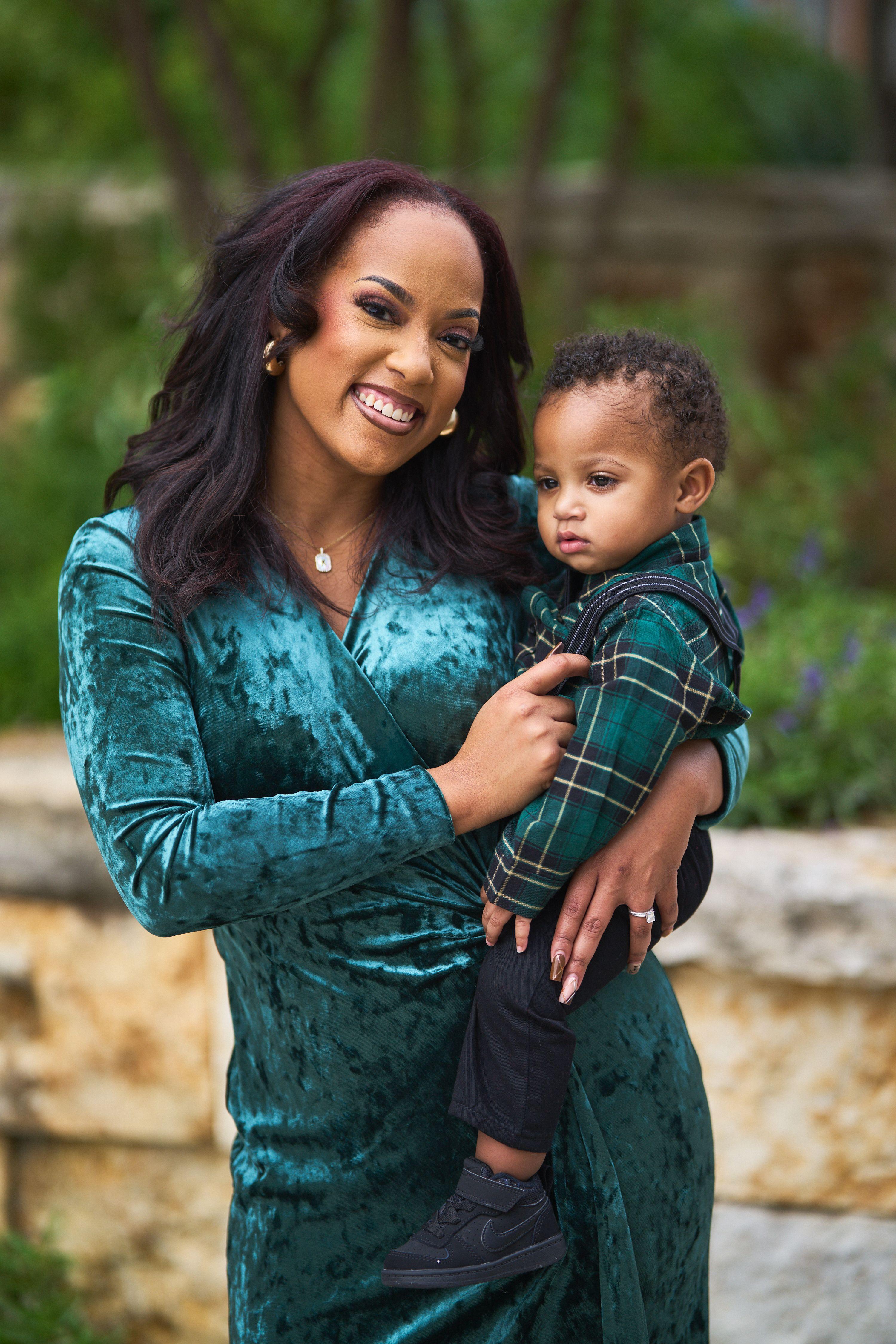 Mother in green velvet holding her toddler against a limestone wall — Seasonal Christmas & Fall photography, Austin A mother in green velvet holding her toddler against a limestone wall.