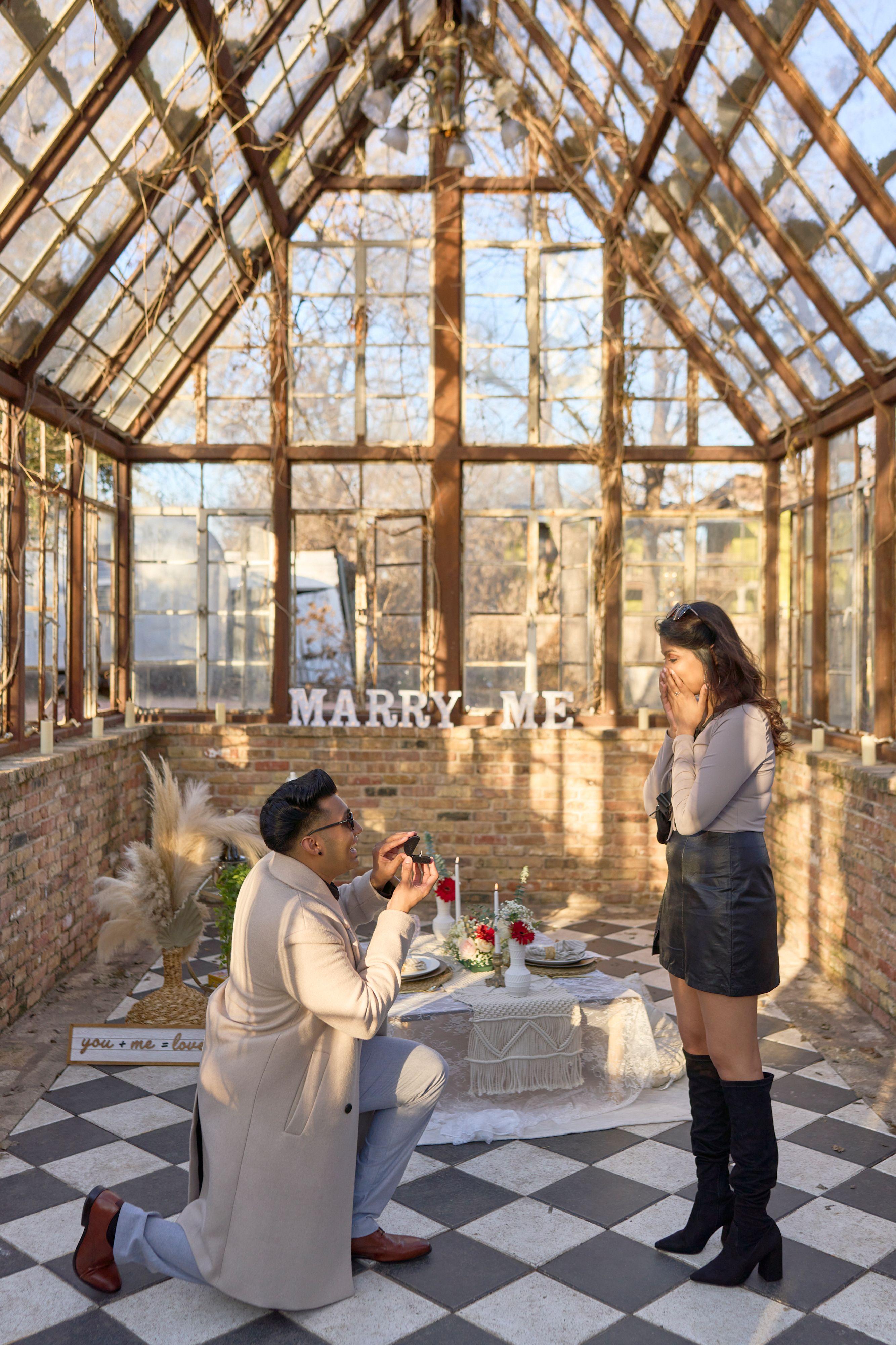 Glass conservatory at Sekrit Theater with MARRY ME letters against the panes and a man — Sekrit Theater photography, Austin The glass conservatory at Sekrit Theater with MARRY ME letters against the panes and a man on one knee on the checkerboard floor