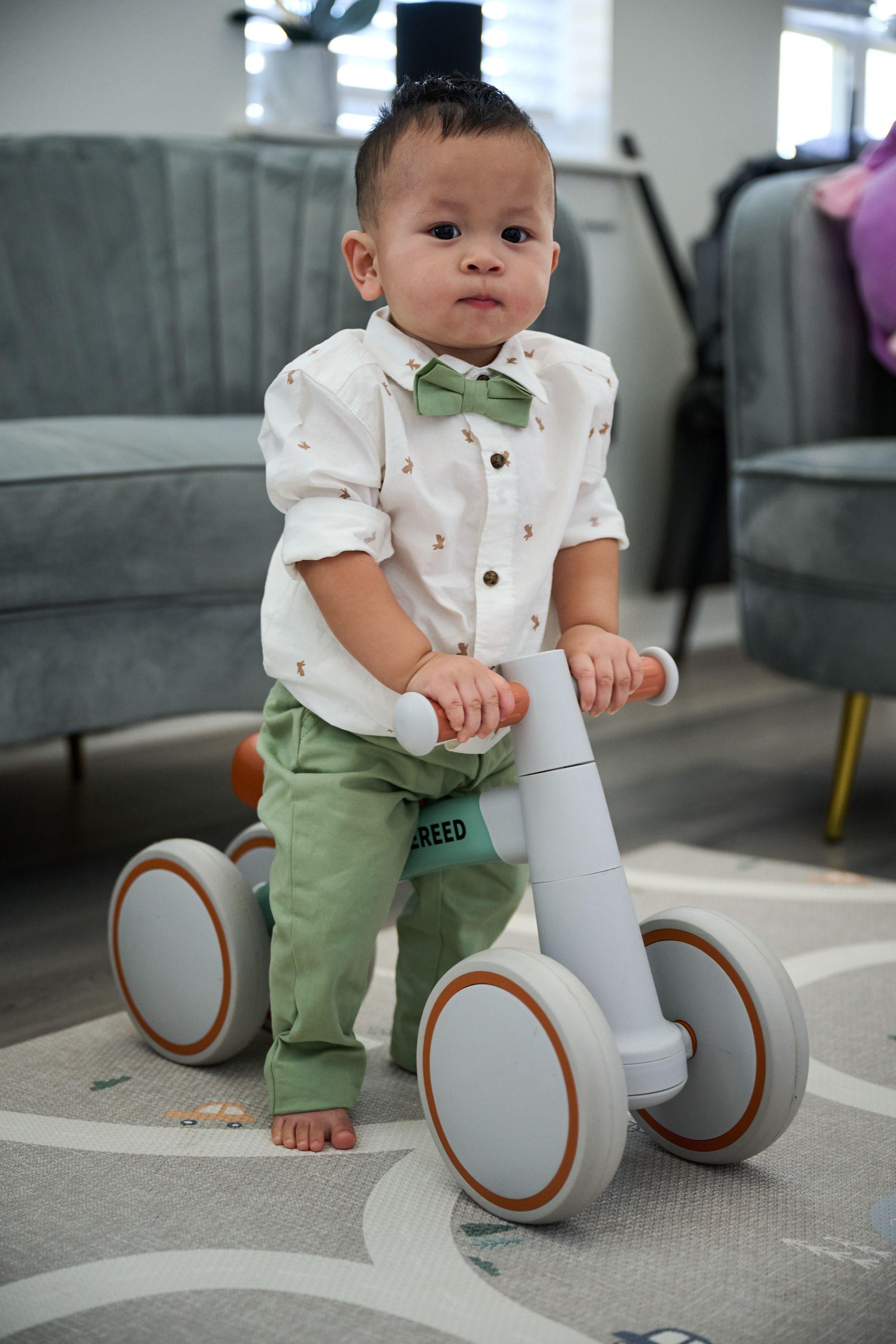 Toddler on a small wooden balance bike in a living room — Kids Portraits photography, Austin A toddler on a small wooden balance bike in a living room.