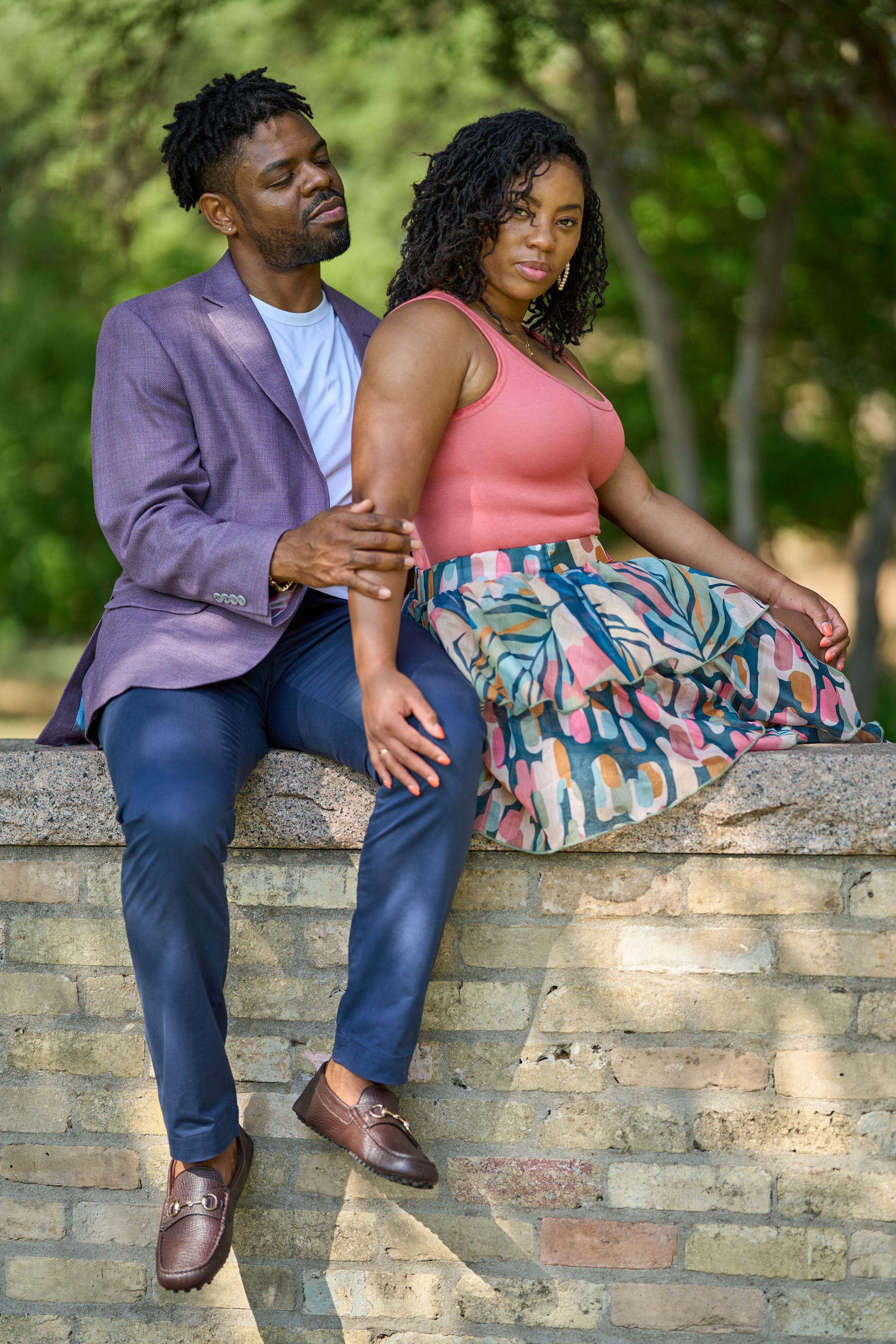 Woman in a floral skirt seated on a low stone wall with a man in a purple blazer standing — Zilker Botanical Gardens photography, Austin A woman in a floral skirt seated on a low stone wall with a man in a purple blazer standing beside her