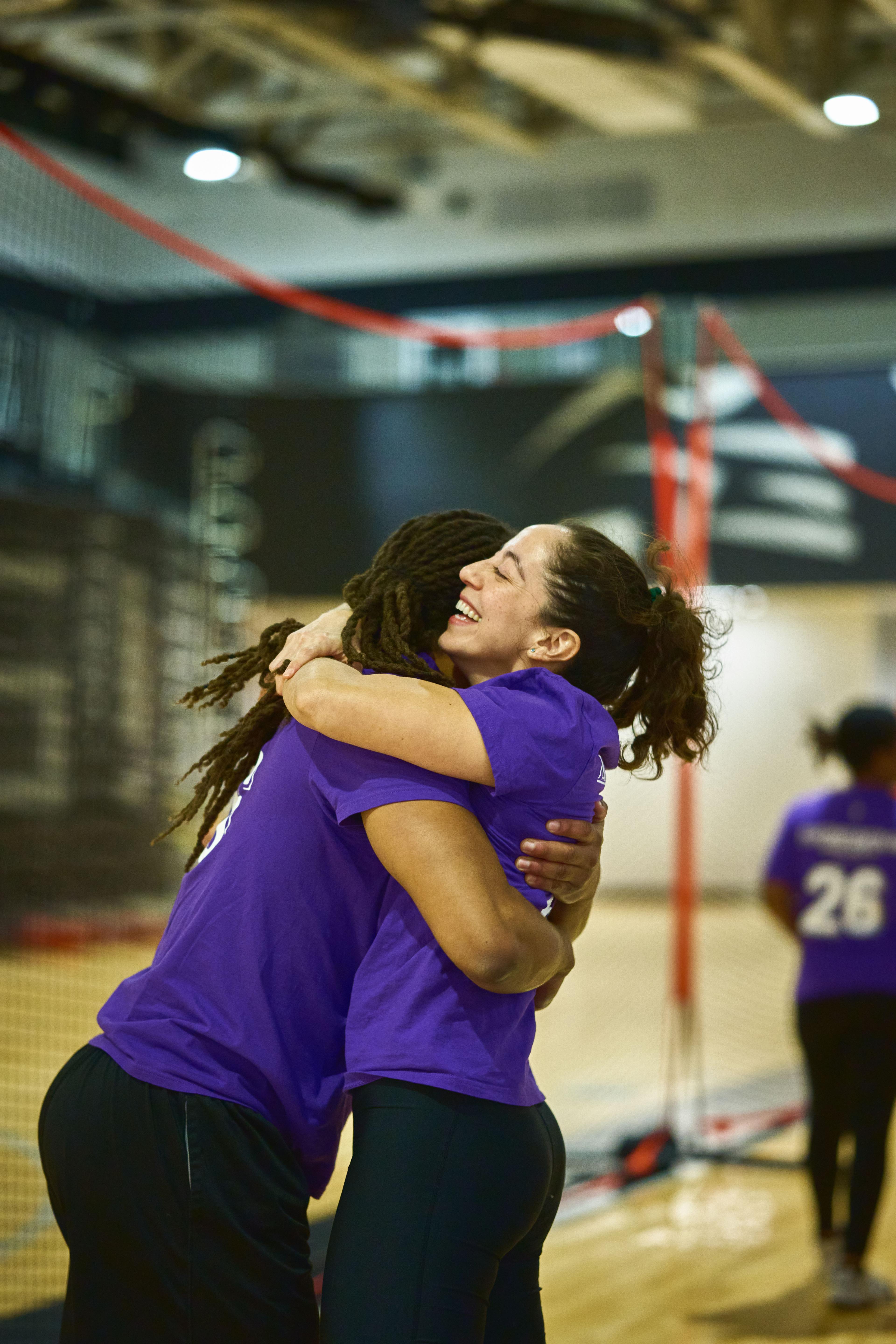 Two volleyball players in purple embracing after a point in an indoor court — Sports photography, Austin Two volleyball players in purple embracing after a point in an indoor court