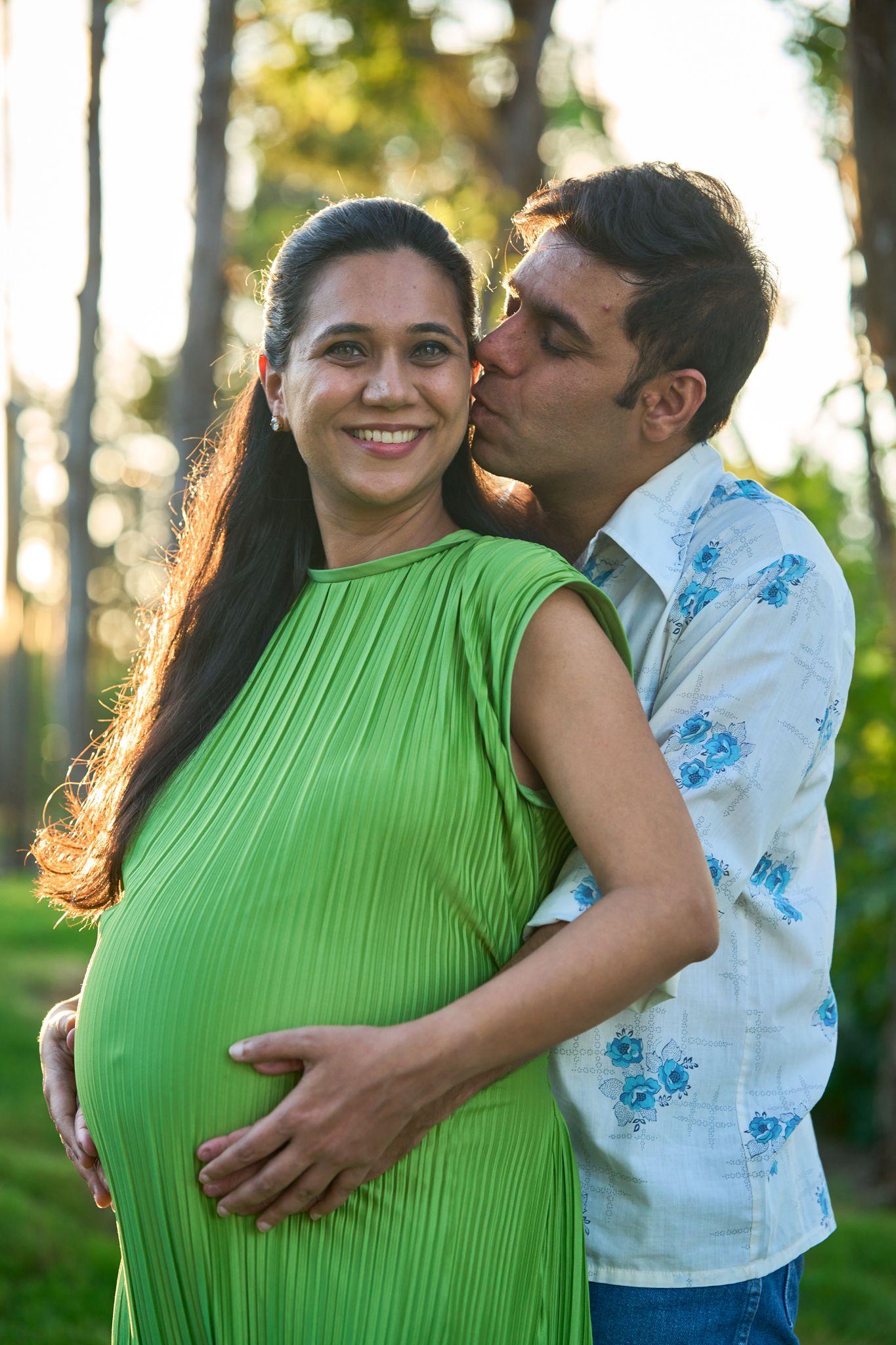 Partner kissing an expectant mother in a green dress — Maternity photography, Austin Partner kissing an expectant mother in a green dress