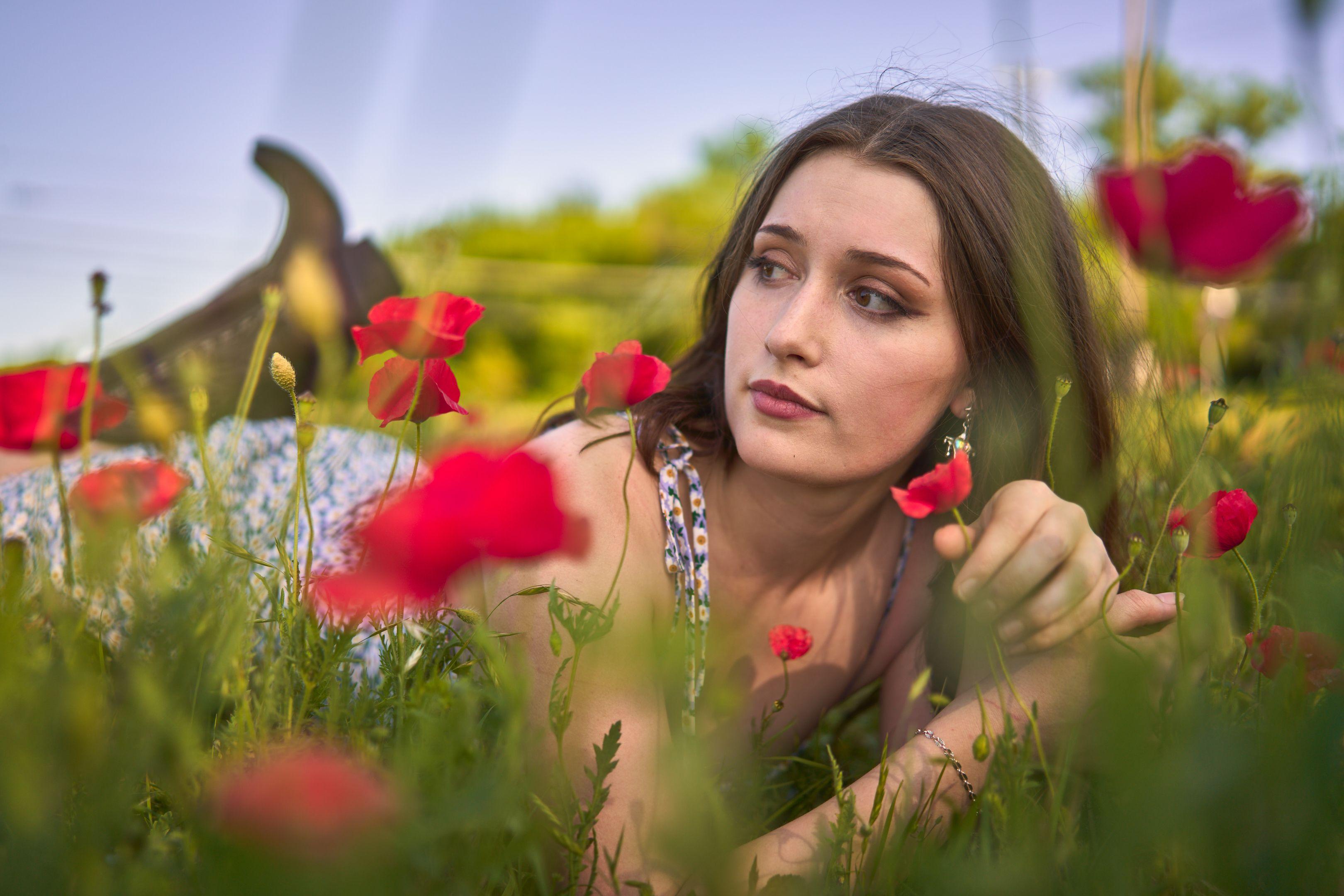 Young woman lying among red poppies, looking away from camera — Seasonal Wildflower Season in Texas photography, Austin A young woman lying among red poppies, looking away from camera.