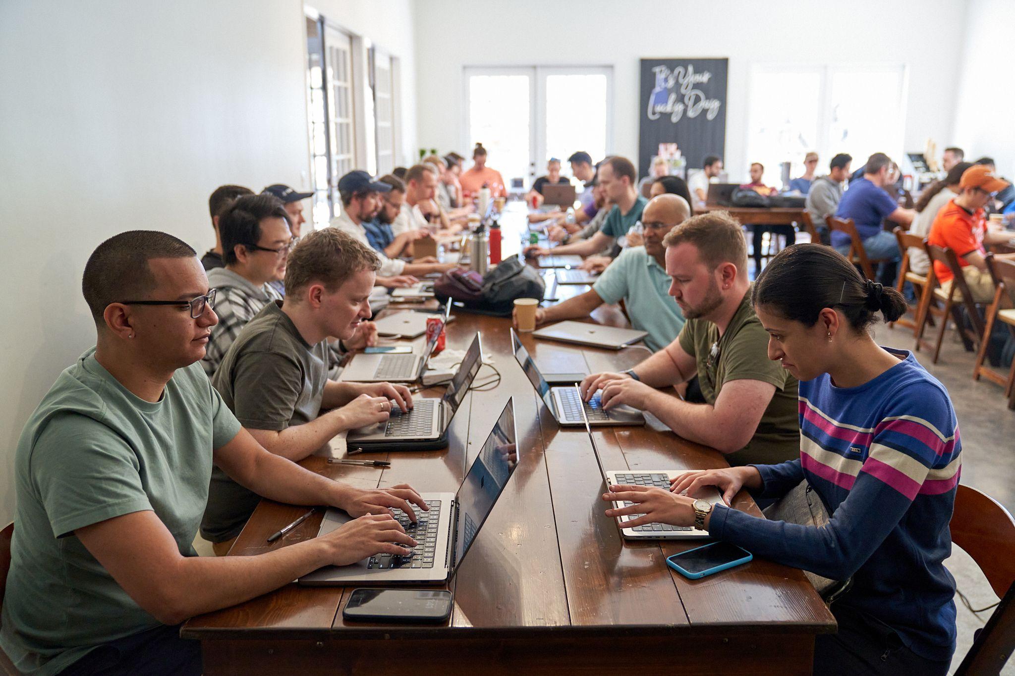 Long shared table of people working on laptops at an offsite session — Team offsite photography, Austin A long shared table of people working on laptops at an offsite session