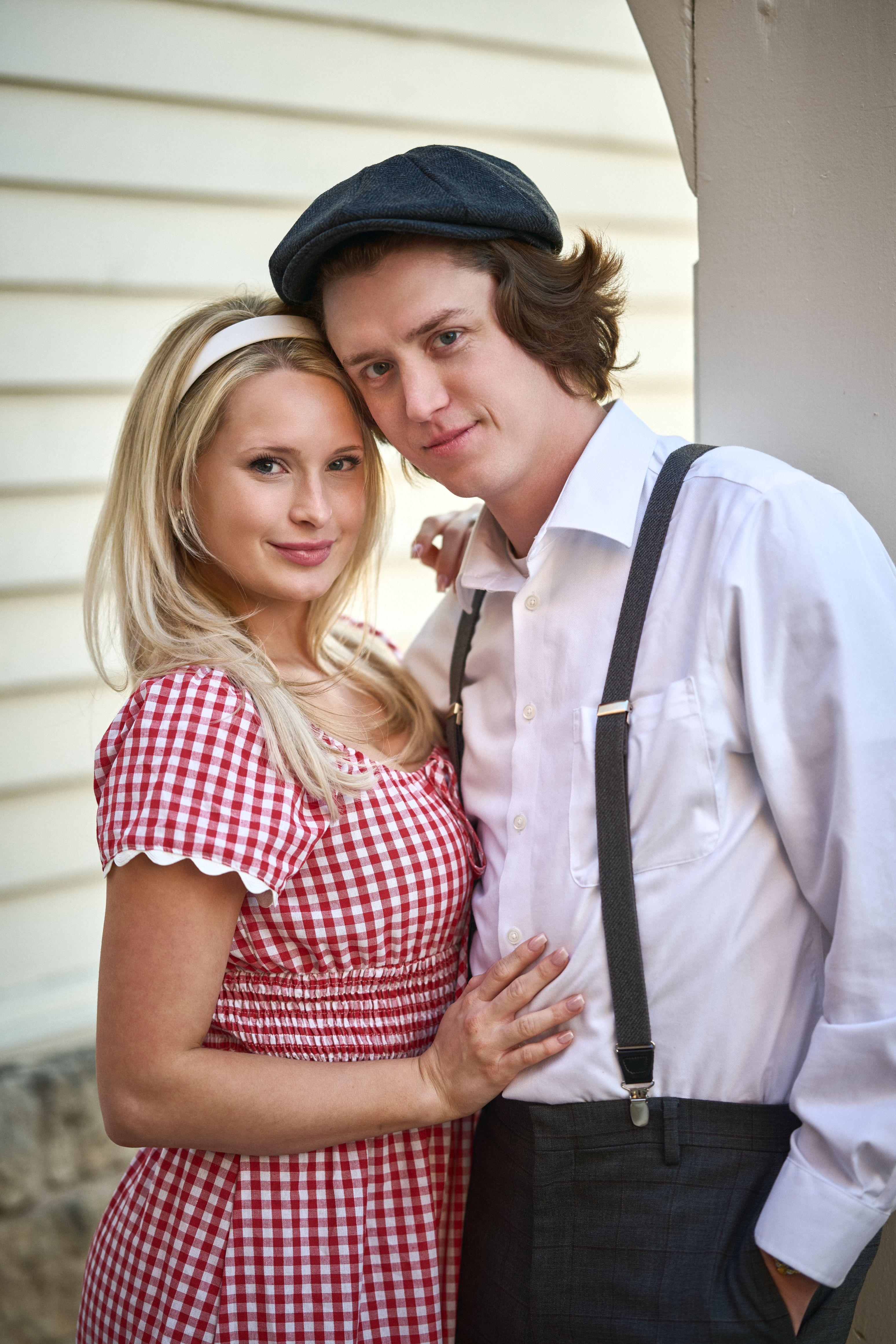 Couple in 1940s styling standing against a white clapboard wall on the Georgetown square — Georgetown Downtown photography, Austin A couple in 1940s styling standing against a white clapboard wall on the Georgetown square