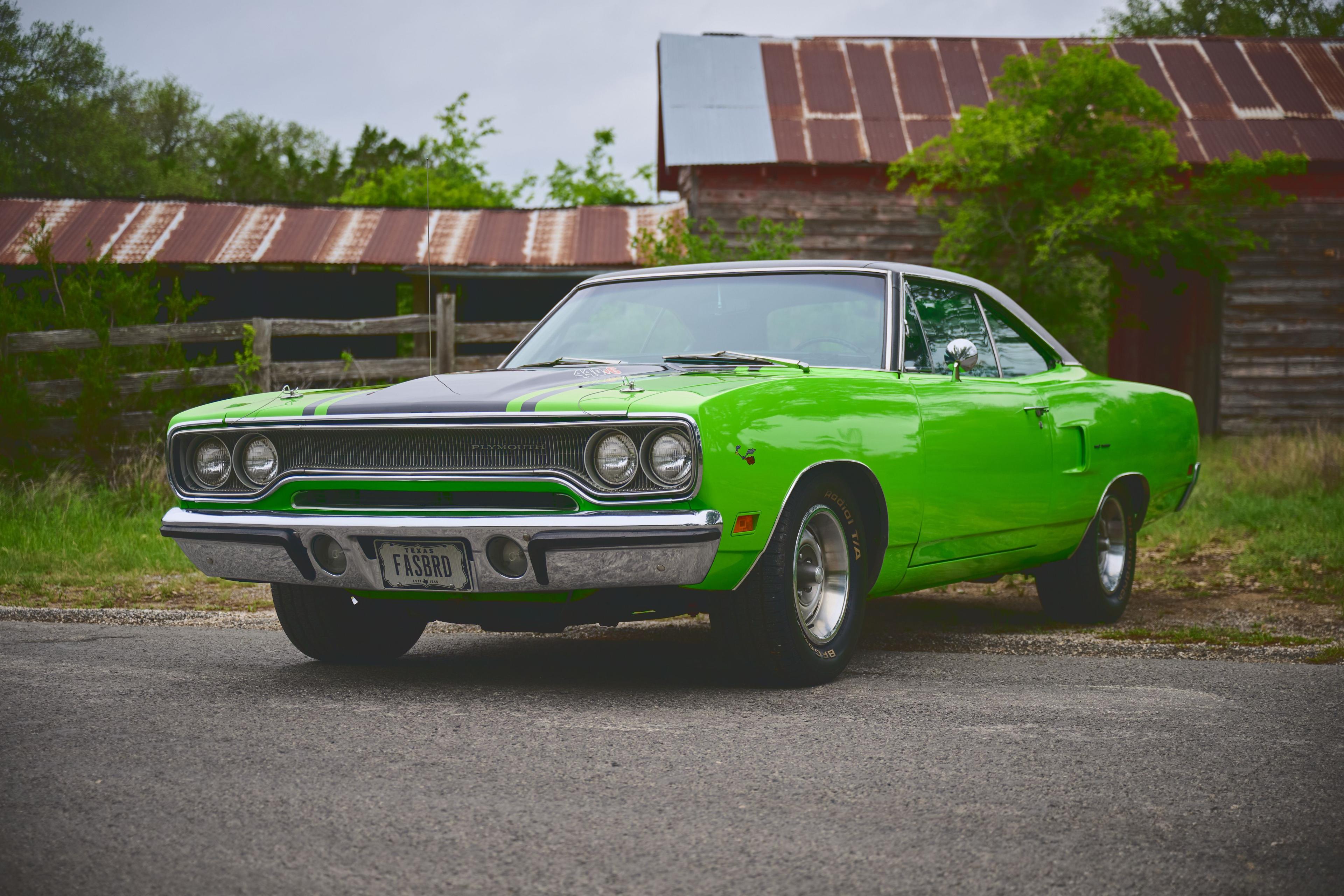 Bright green classic Plymouth muscle car parked beside a barn — Automotive photography, Austin A bright green classic Plymouth muscle car parked beside a barn.