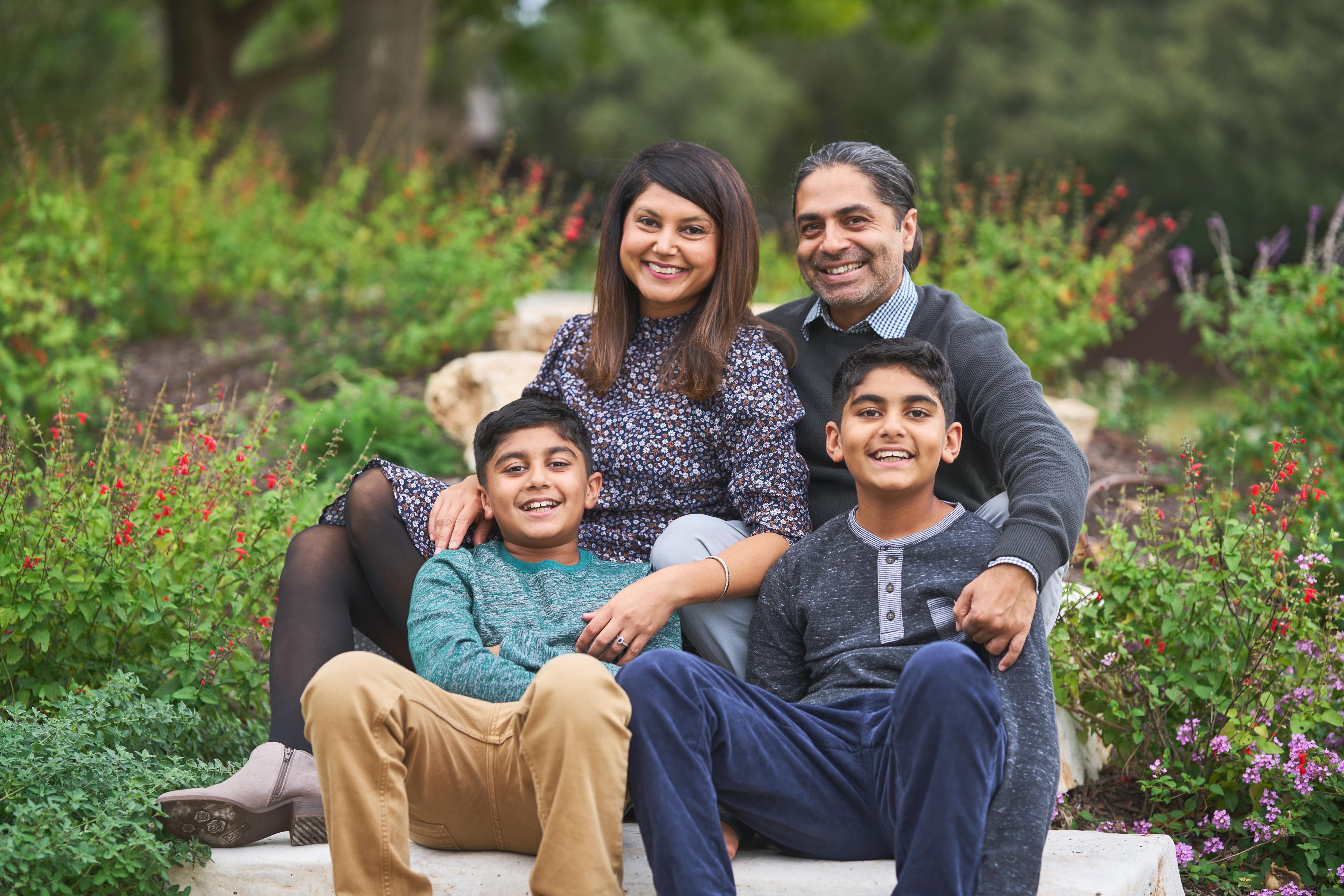 Family of four seated on a limestone bench at Olson Meadows Park with flowering shrubs — Olson Meadows Park photography, Austin A family of four seated on a limestone bench at Olson Meadows Park with flowering shrubs behind them