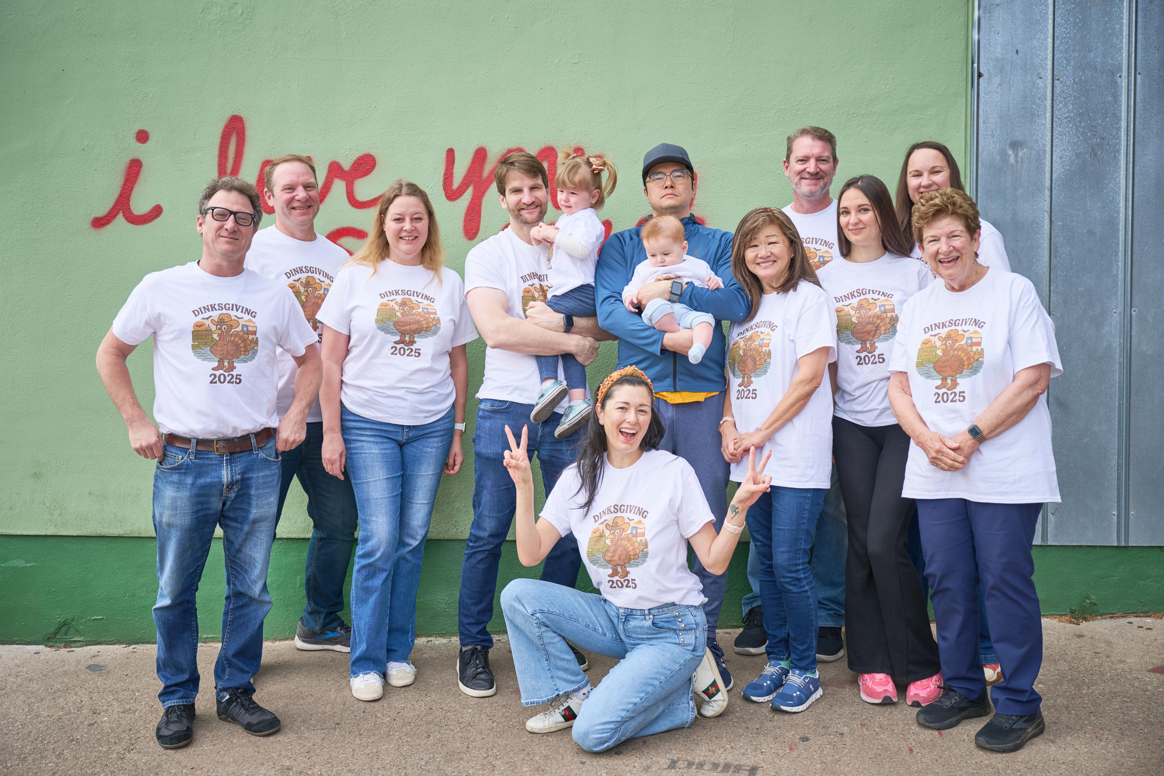 Extended family in matching printed shirts gathered at the mural wall — Family Portraits photography, Austin An extended family in matching printed shirts gathered at the mural wall, one throwing a peace sign.