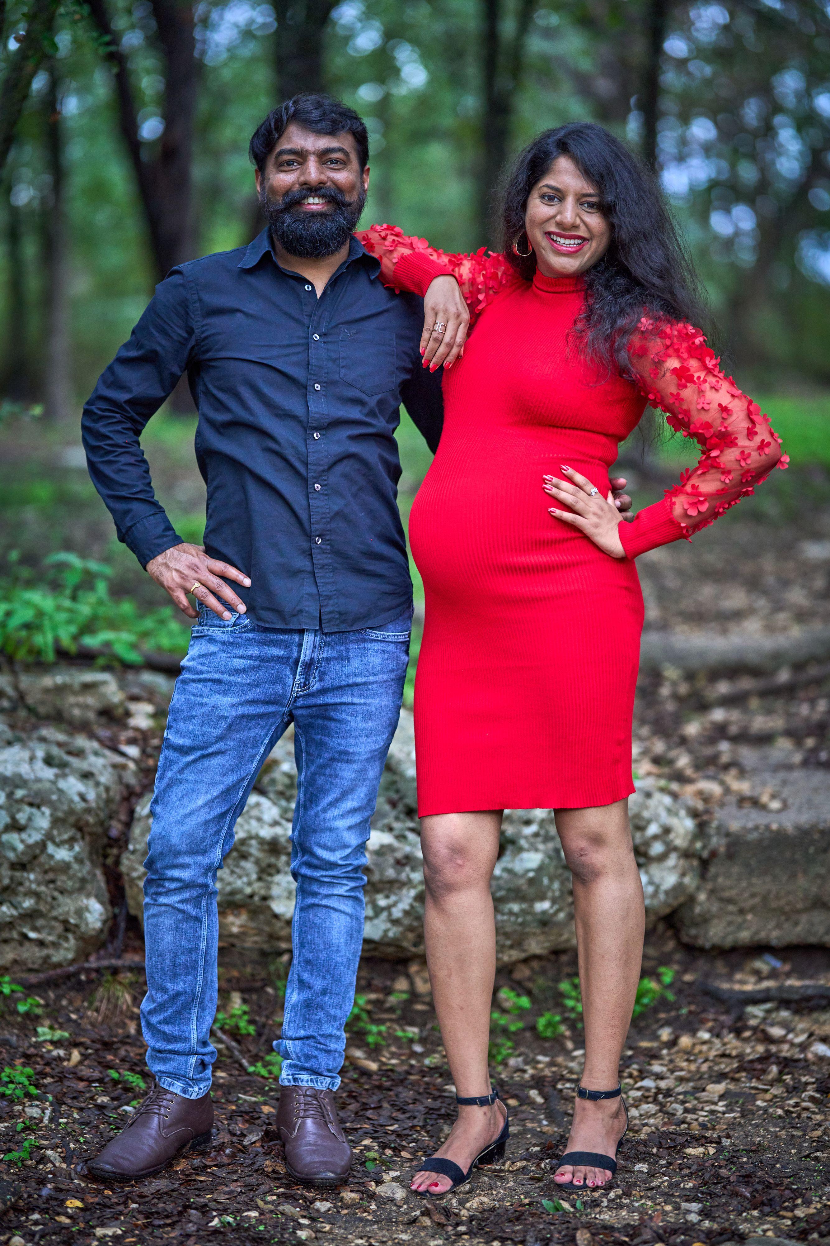 Expectant couple standing on the bank at Blue Hole Park, the woman in a red dress, limestone — Georgetown Blue Hole Park photography, Austin An expectant couple standing on the bank at Blue Hole Park, the woman in a red dress, limestone and trees behind them