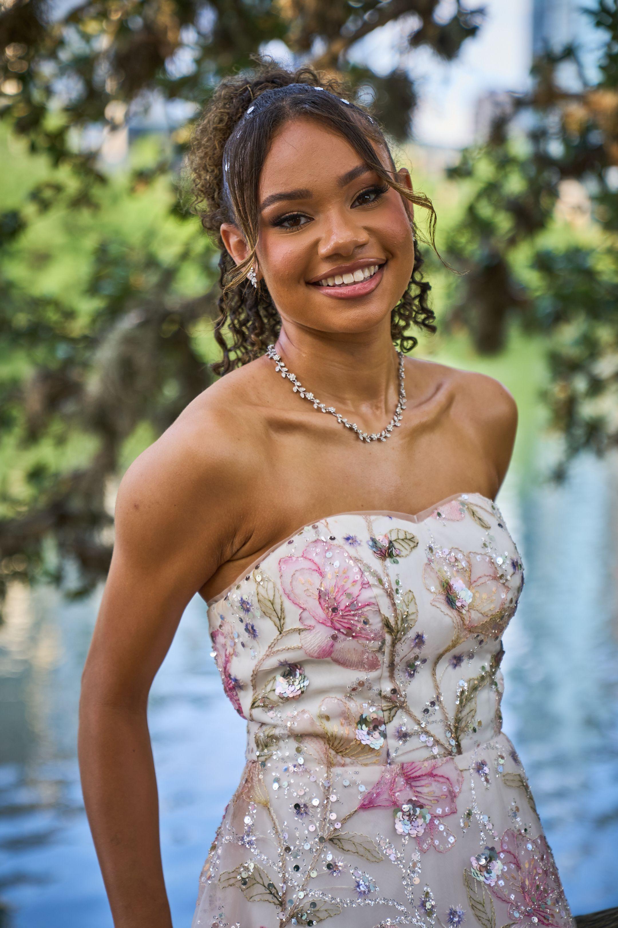 Young woman in an embroidered floral prom gown smiling under green trees — Butler Metro Park photography, Austin A young woman in an embroidered floral prom gown smiling under green trees.