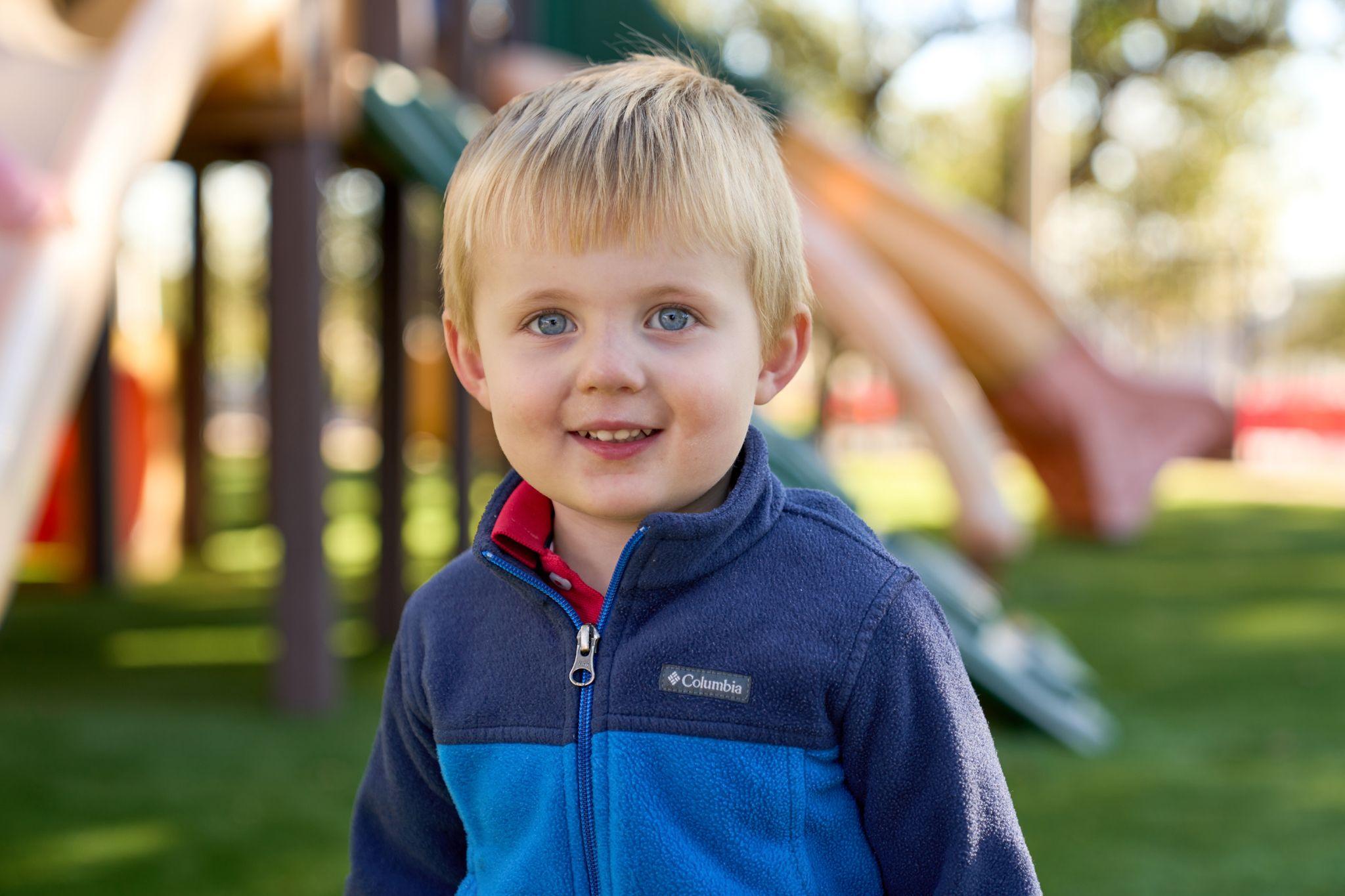 Young boy in a blue fleece smiling in warm outdoor light — School event photography, Austin Young boy in a blue fleece smiling in warm outdoor light