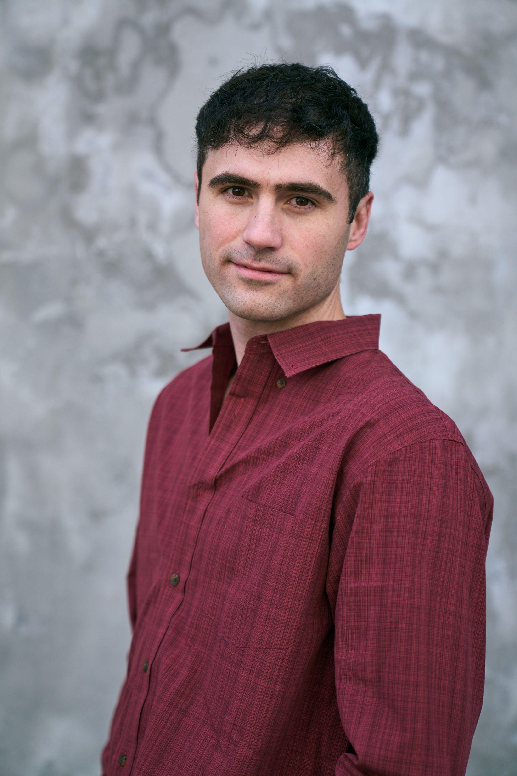 Portrait of a man in a red shirt against a pale textured downtown wall — Downtown Austin photography, Austin A portrait of a man in a red shirt against a pale textured downtown wall.