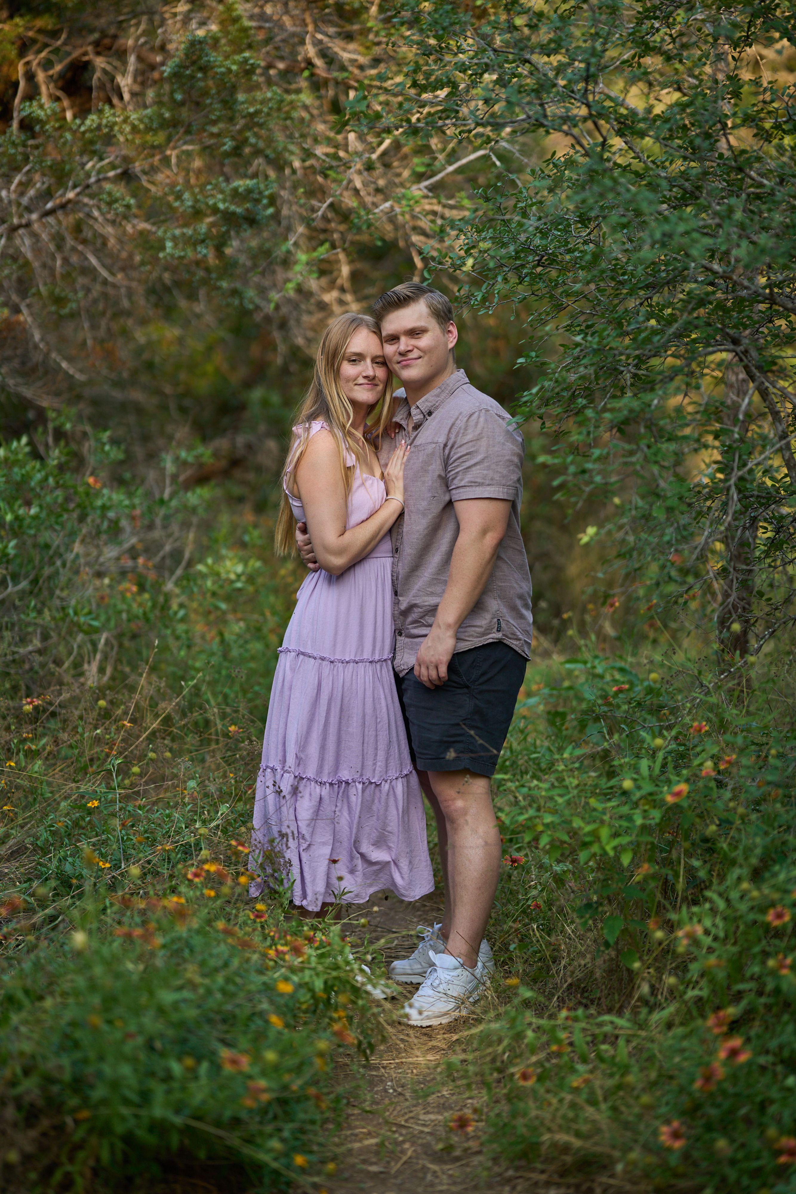 Couple in the woods at Mayfield Park, the woman in a pink dress leaning back against him — Mayfield Park photography, Austin A couple in the woods at Mayfield Park, the woman in a pink dress leaning back against him