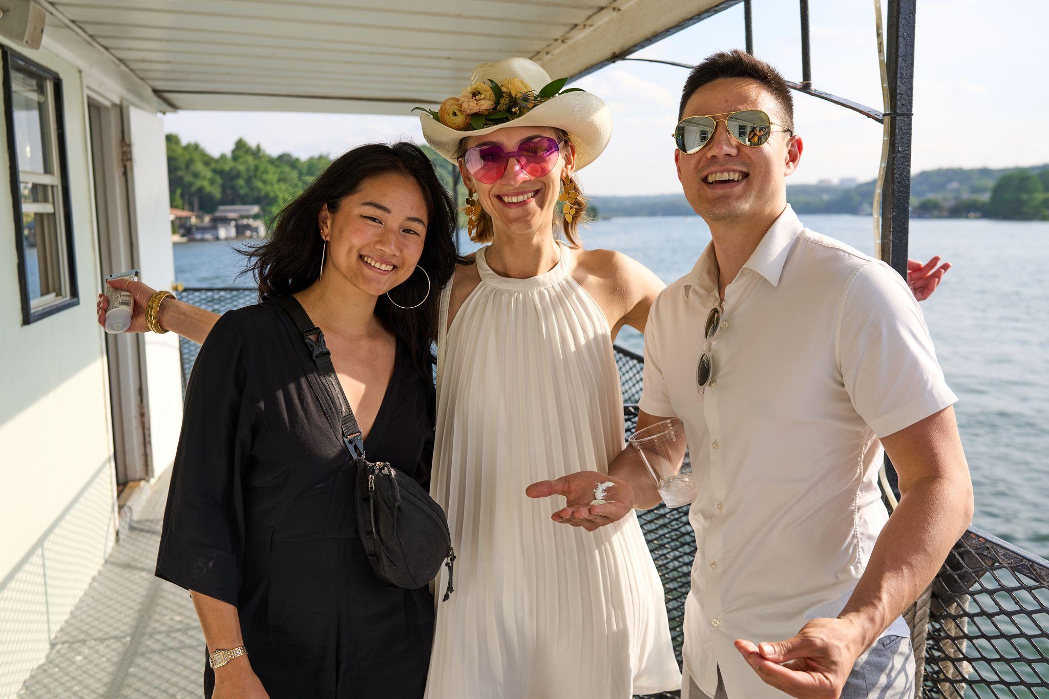 Three guests in sunhats and sunglasses laughing together aboard a party boat — Formal Celebrations photography, Austin Three guests in sunhats and sunglasses laughing together aboard a party boat.