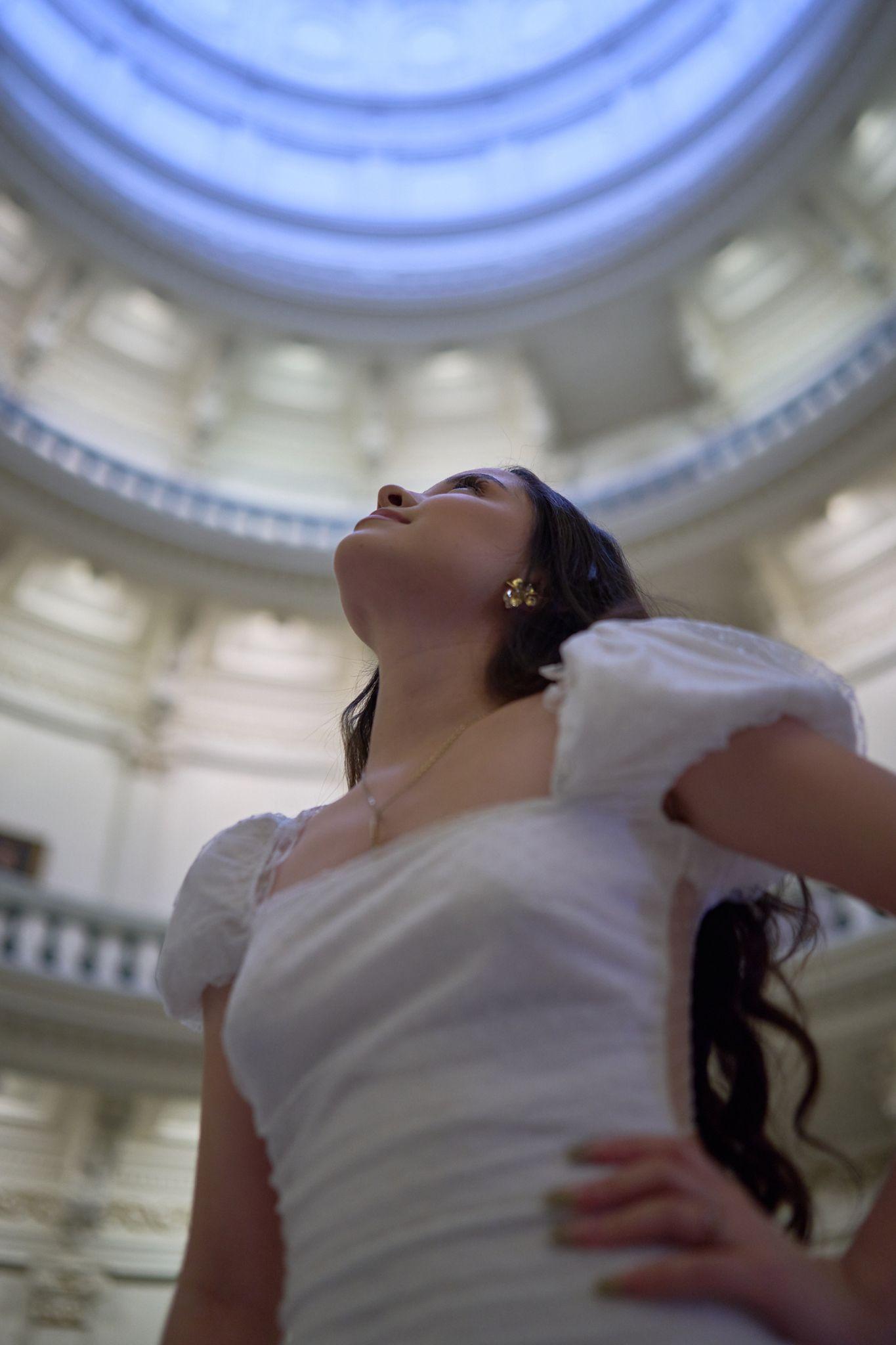 Woman in white leaning back and laughing directly beneath the Capitol dome — Texas State Capitol photography, Austin A woman in white leaning back and laughing directly beneath the Capitol dome.