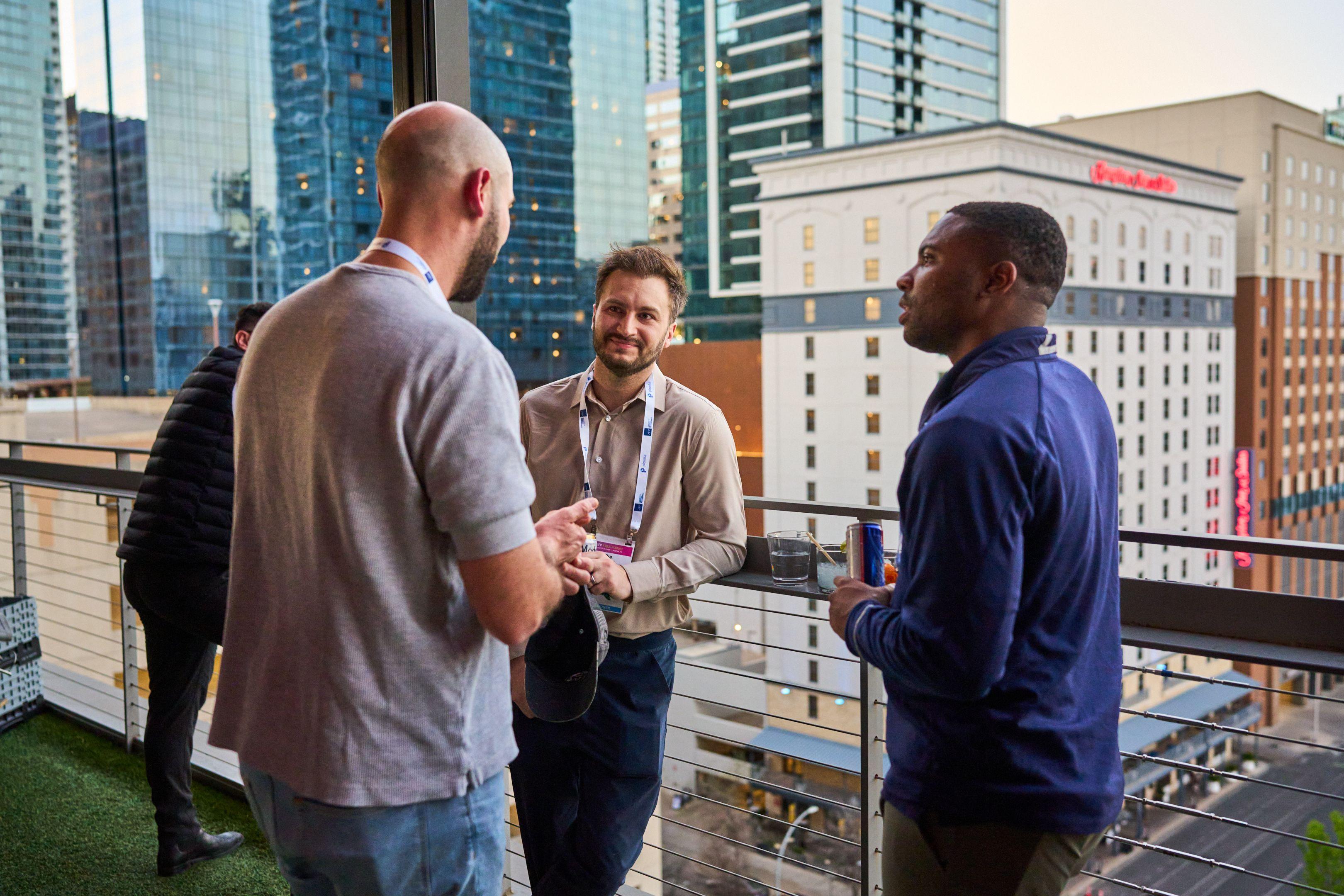 Three colleagues laughing together on a rooftop terrace with high-rise towers behind them — Business Parties photography, Austin Three colleagues laughing together on a rooftop terrace with high-rise towers behind them.