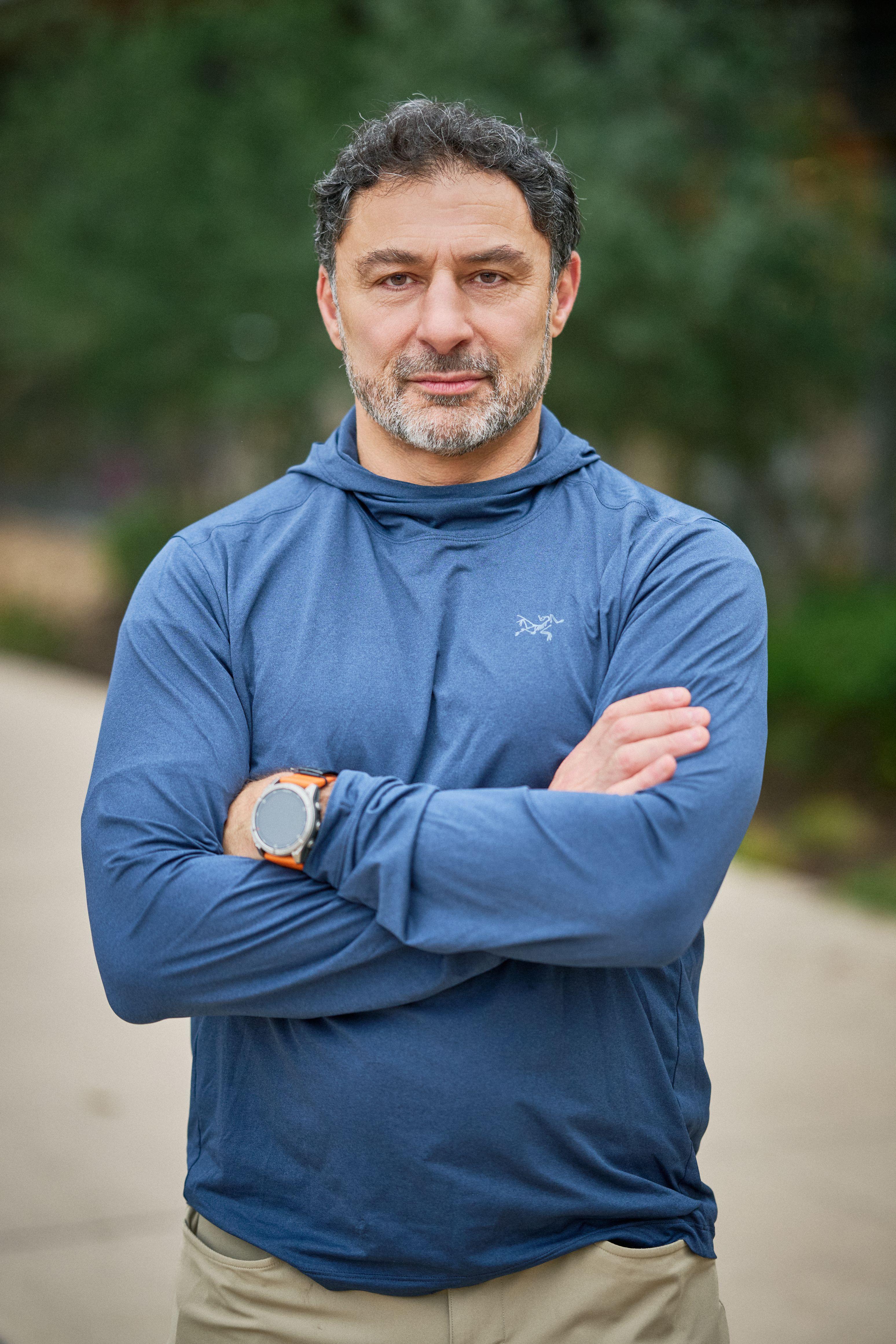 Man in a blue hoodie standing with his arms crossed on a path in The Domain — The Domain photography, Austin A man in a blue hoodie standing with his arms crossed on a path in The Domain