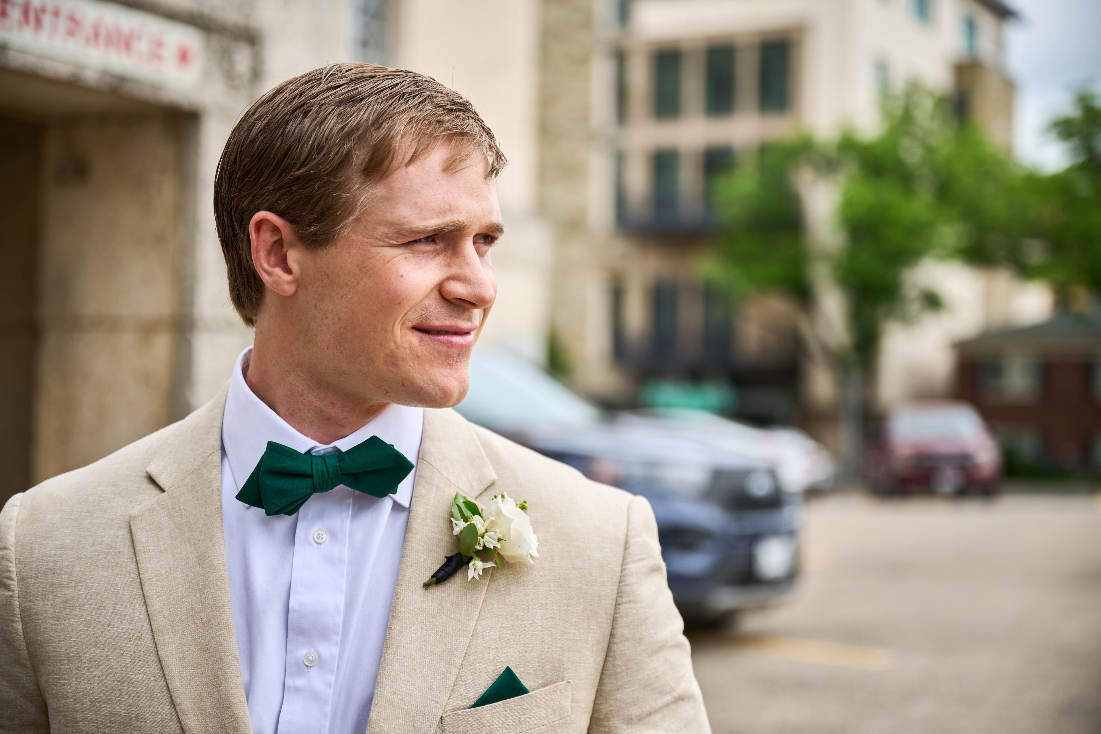 Portrait of a groom in a cream suit and green bow tie outside the courthouse — Elopements photography, Austin A portrait of a groom in a cream suit and green bow tie outside the courthouse.