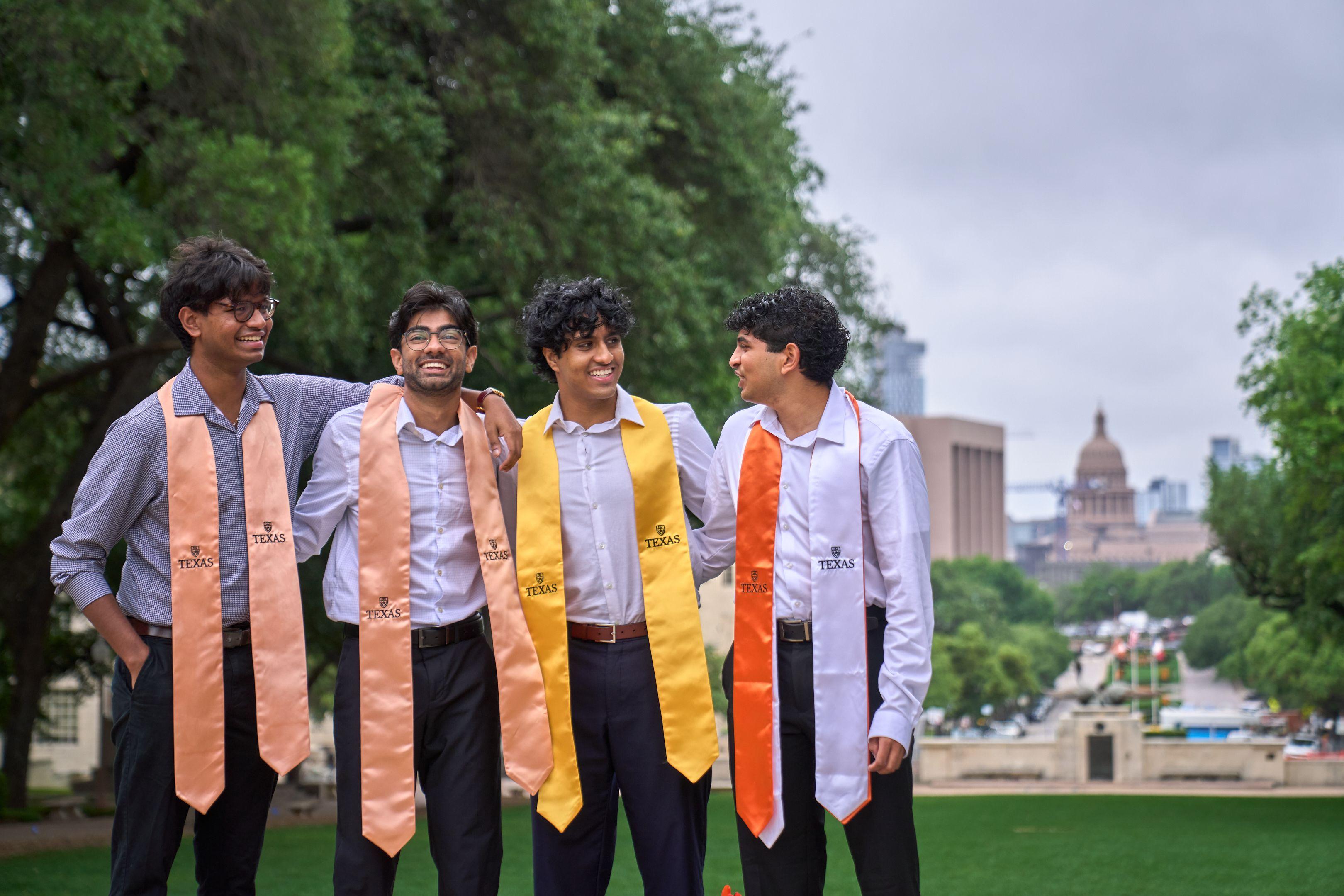 Three graduates in orange and gold stoles laughing together on a green lawn — Graduation & Prom photography, Austin Three graduates in orange and gold stoles laughing together on a green lawn.