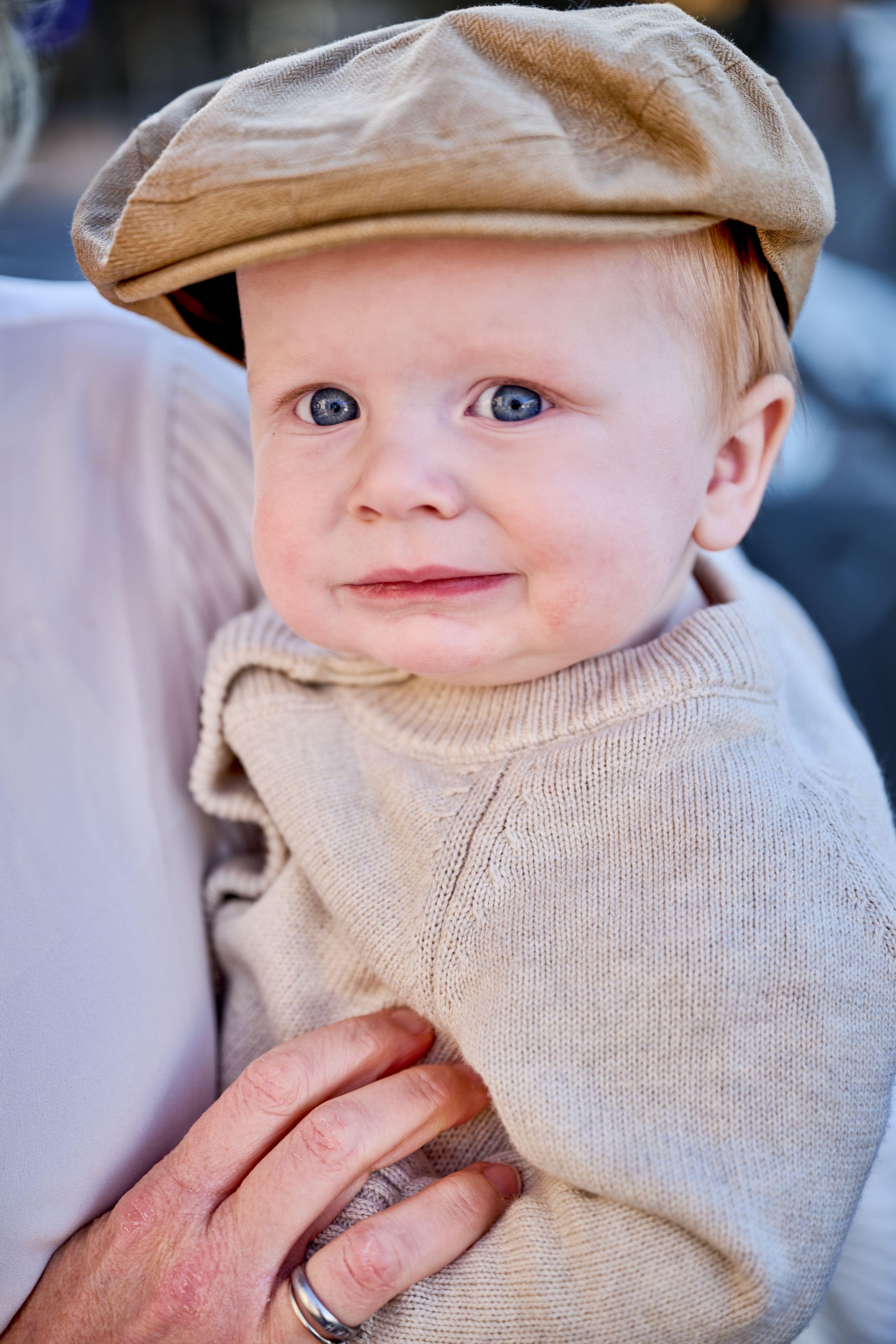 Baby in a tweed newsboy cap held close on the Georgetown square — Georgetown Downtown photography, Austin A baby in a tweed newsboy cap held close on the Georgetown square