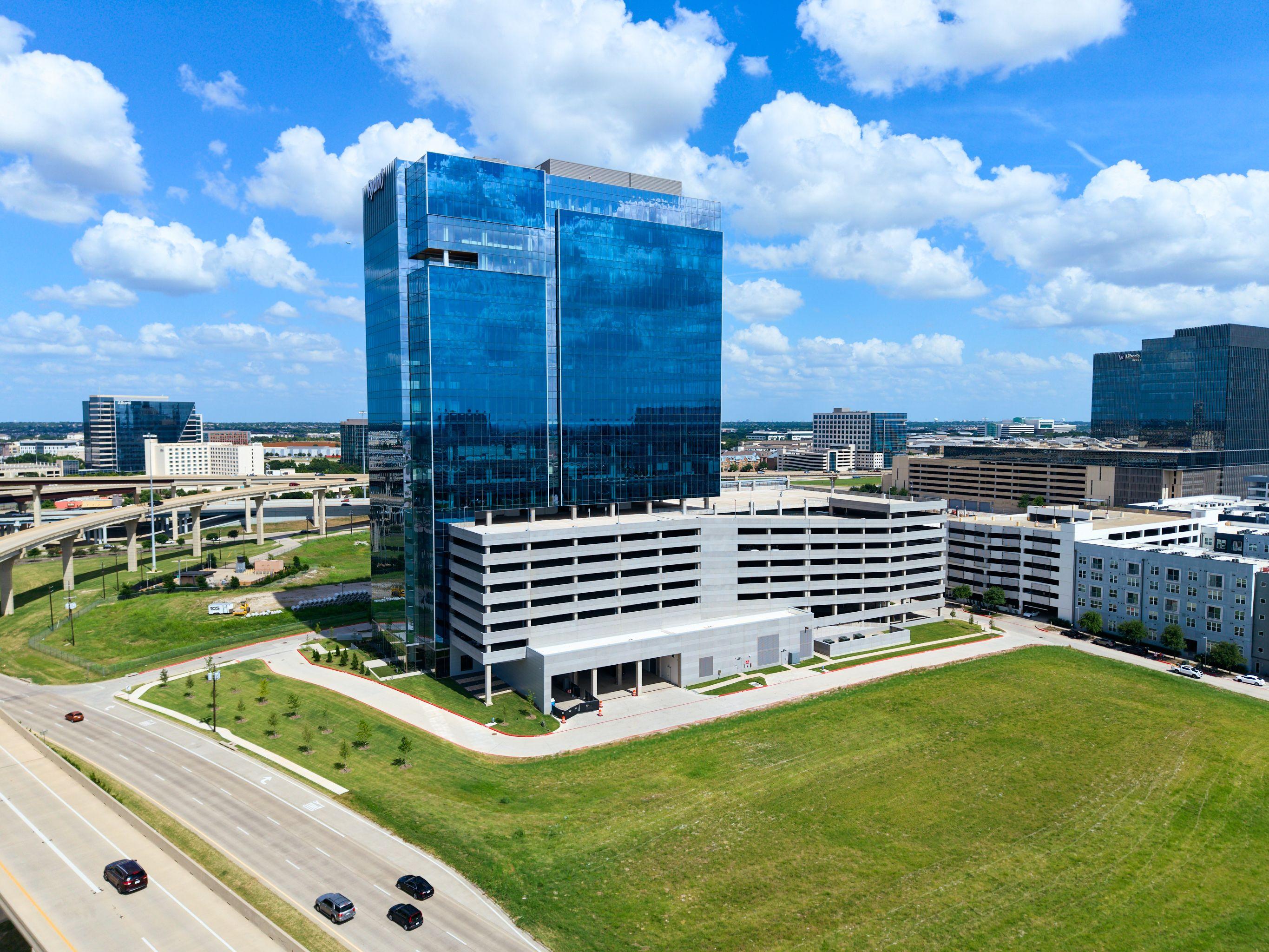 Blue glass office tower beside a white parking structure under a bright sky — Architectural photography, Austin A blue glass office tower beside a white parking structure under a bright sky.