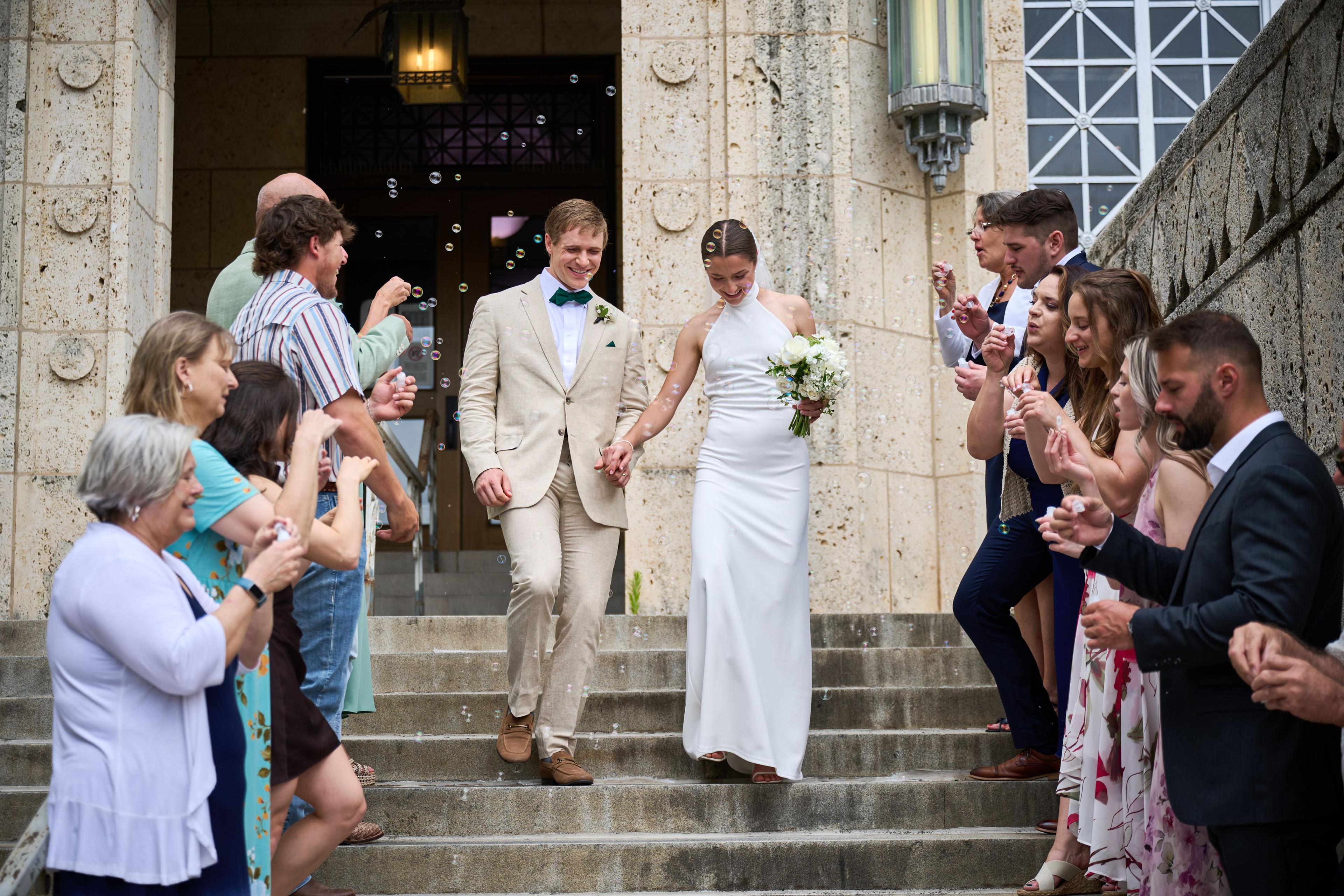 Bride and groom walking down stone courthouse steps through a shower of bubbles — Weddings photography, Austin A bride and groom walking down stone courthouse steps through a shower of bubbles.