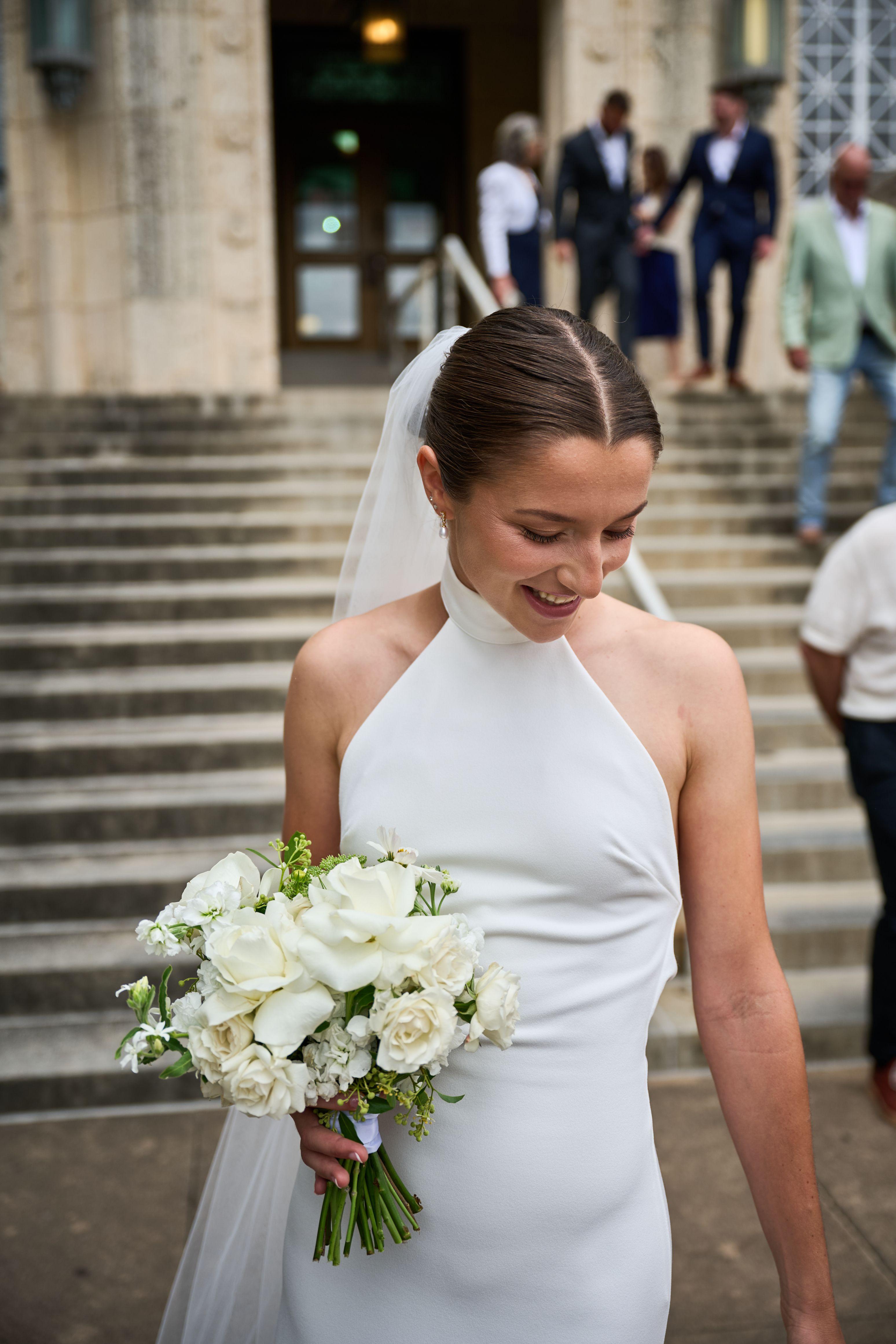 Bride looking down at her white bouquet on the courthouse steps — Elopements photography, Austin A bride looking down at her white bouquet on the courthouse steps.
