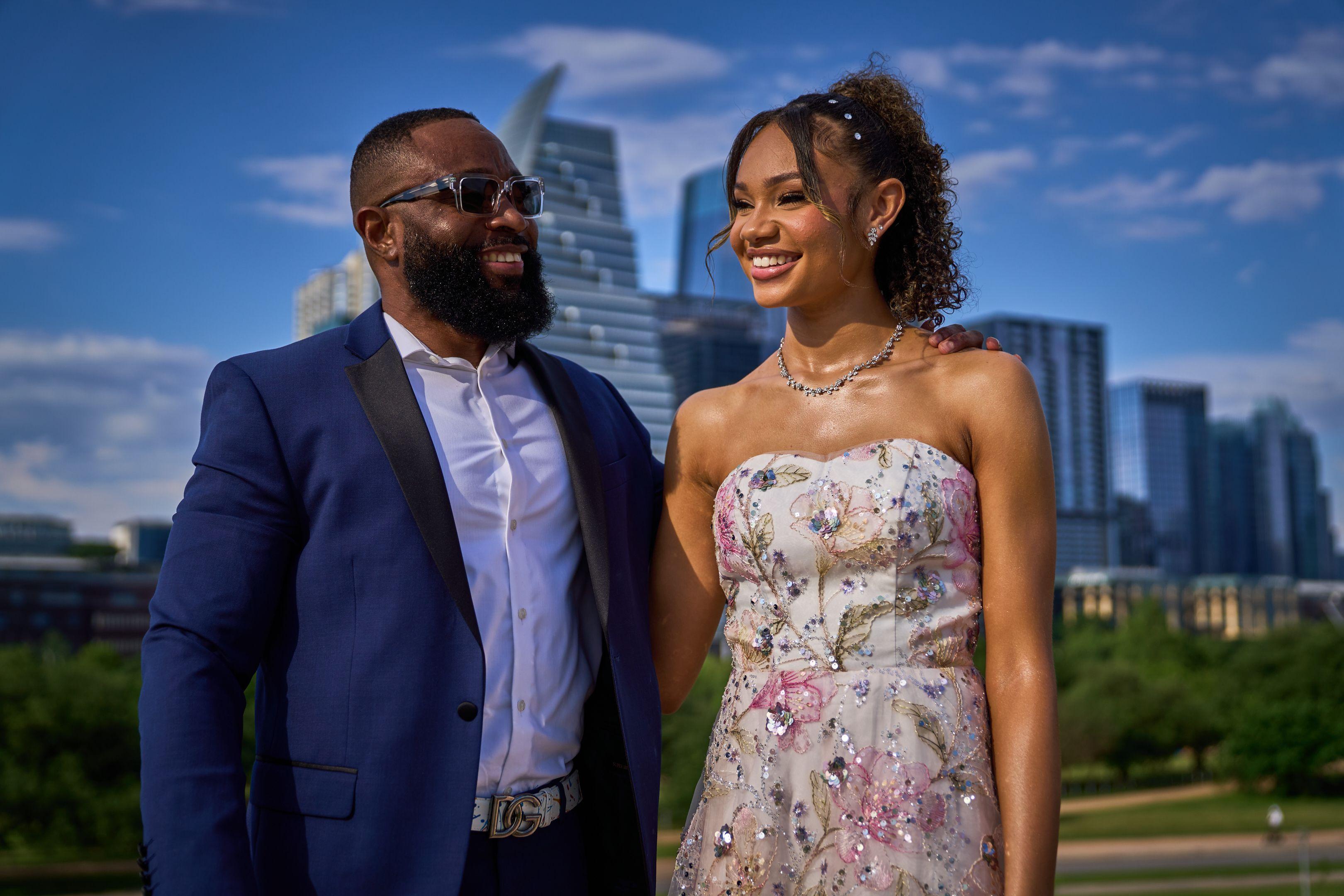 Father in a navy suit laughing with his daughter in a floral prom gown, downtown — Butler Metro Park photography, Austin A father in a navy suit laughing with his daughter in a floral prom gown, downtown behind.