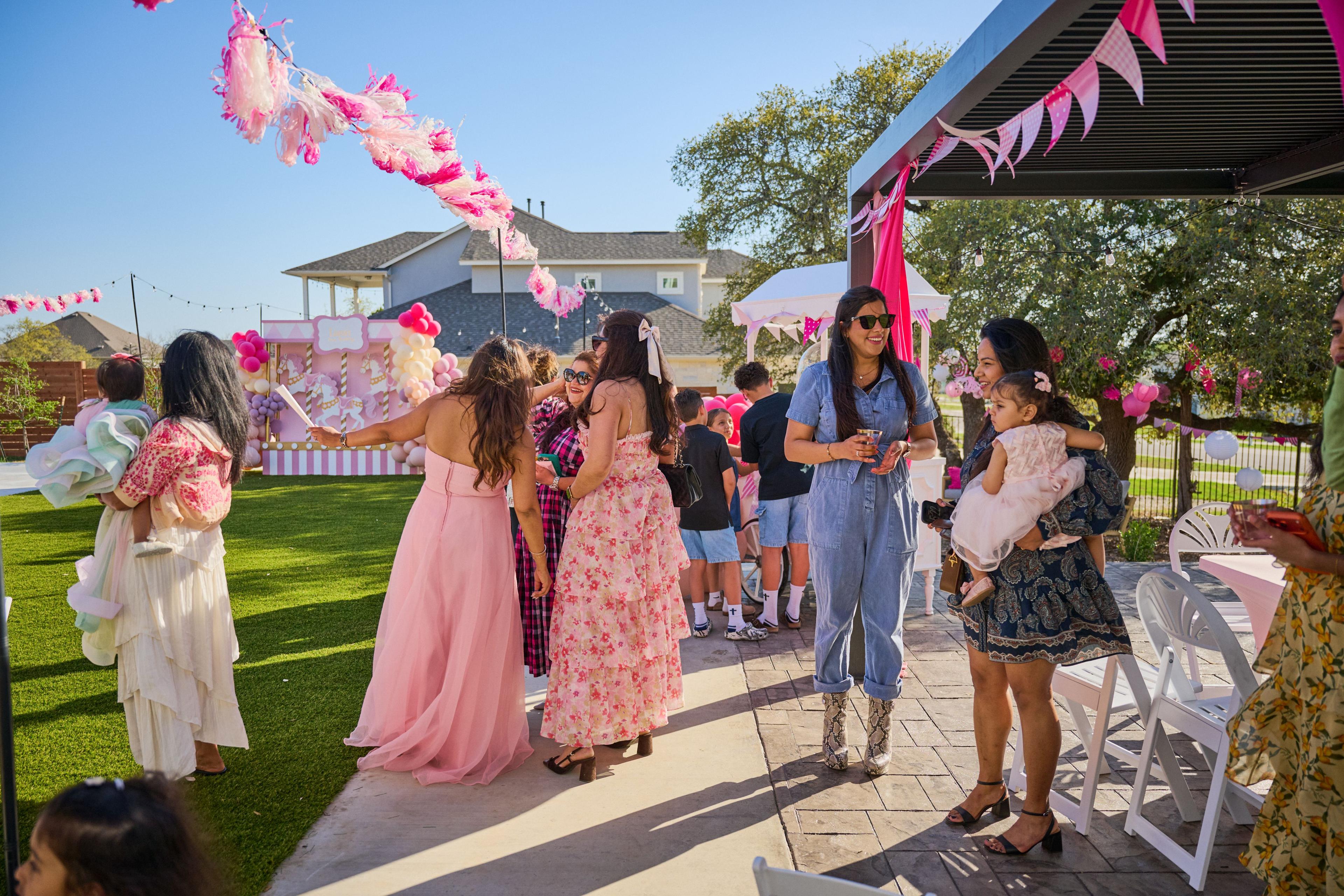Guests in pink and floral dresses arriving along a path lined with pink tassel garlands — Family Parties photography, Austin Guests in pink and floral dresses arriving along a path lined with pink tassel garlands.