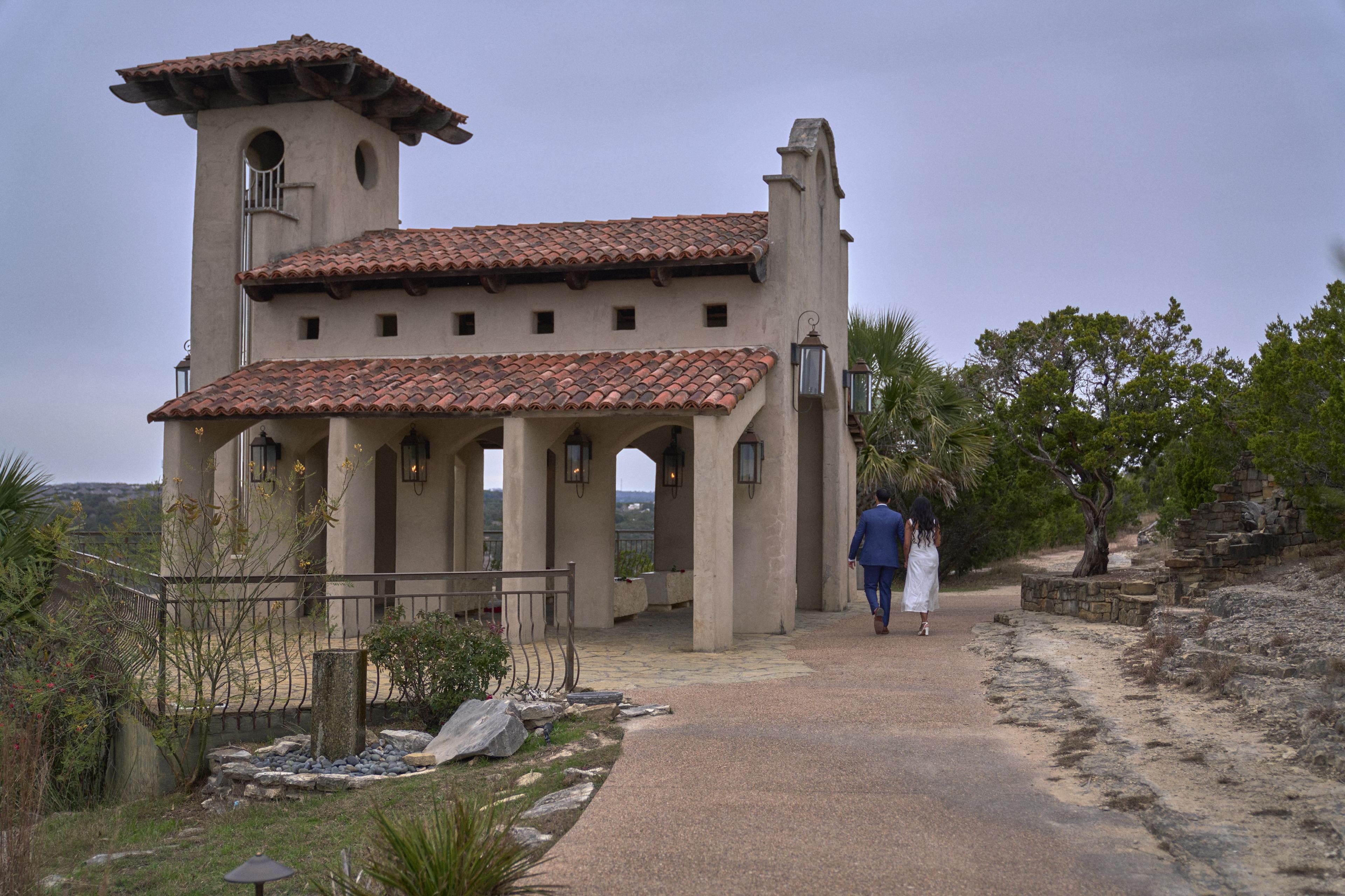 Spanish-tile chapel at Chapel Dulcinea with a couple walking up the path in the distance — Elopements photography, Austin The Spanish-tile chapel at Chapel Dulcinea with a couple walking up the path in the distance.