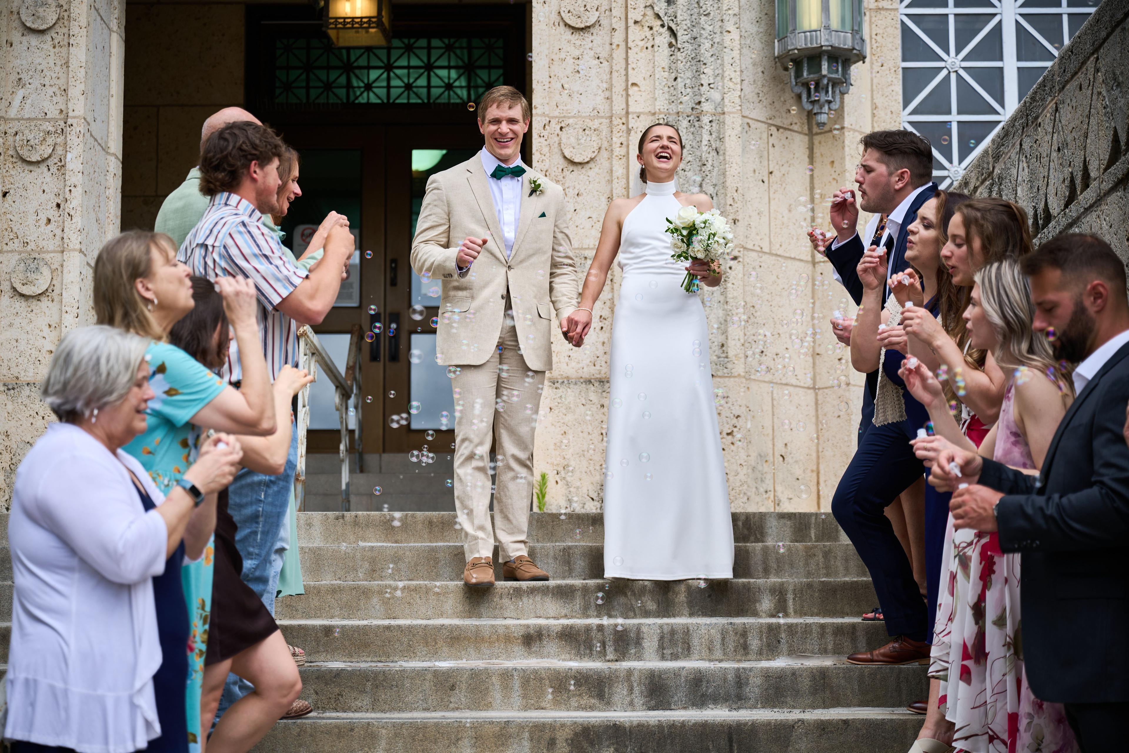 Bride and groom coming down courthouse steps hand in hand through bubbles and guests — Weddings photography, Austin A bride and groom coming down courthouse steps hand in hand through bubbles and guests.