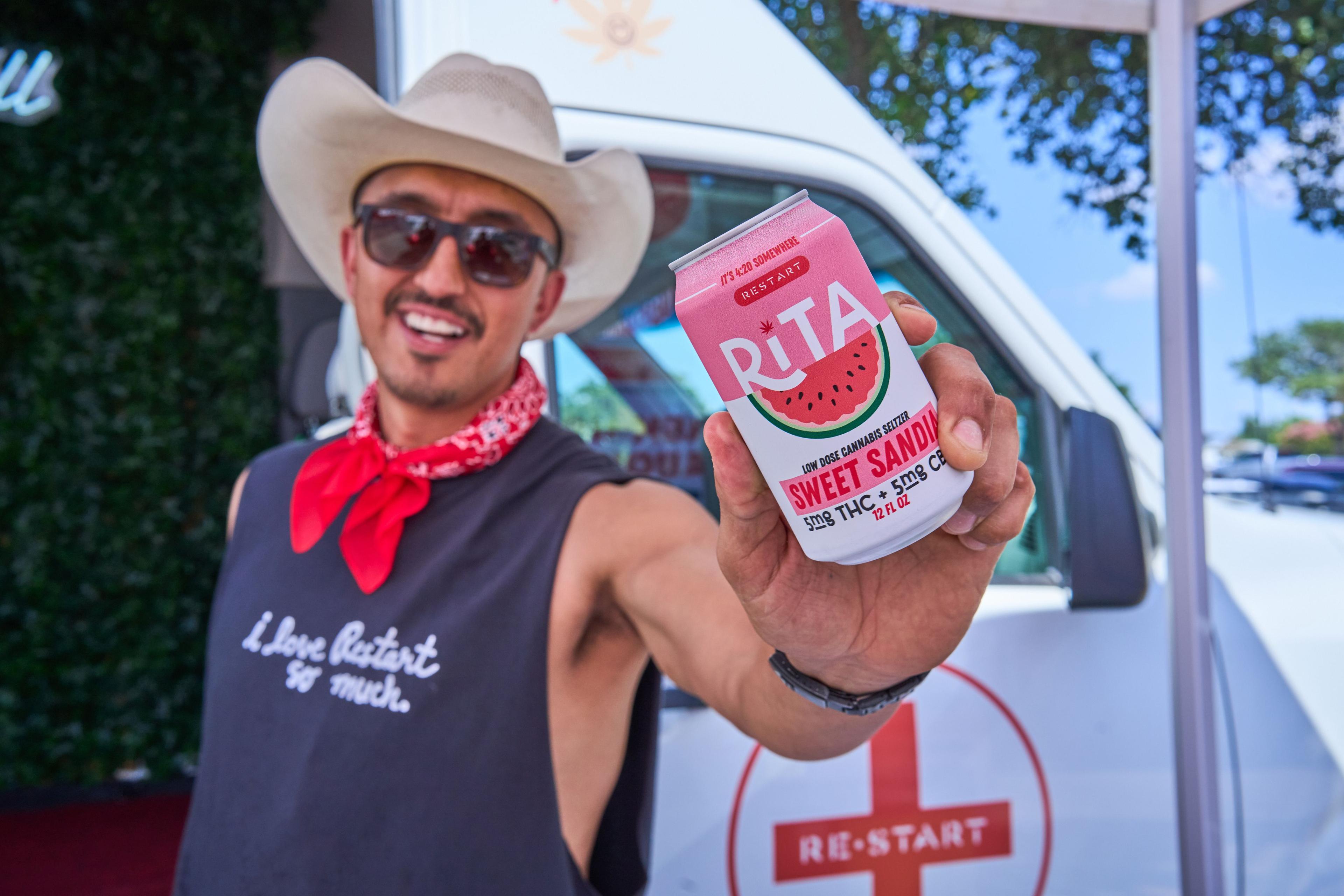 Man in a cowboy hat holding up a canned watermelon cocktail at an outdoor event — Brand activation photography, Austin A man in a cowboy hat holding up a canned watermelon cocktail at an outdoor event.